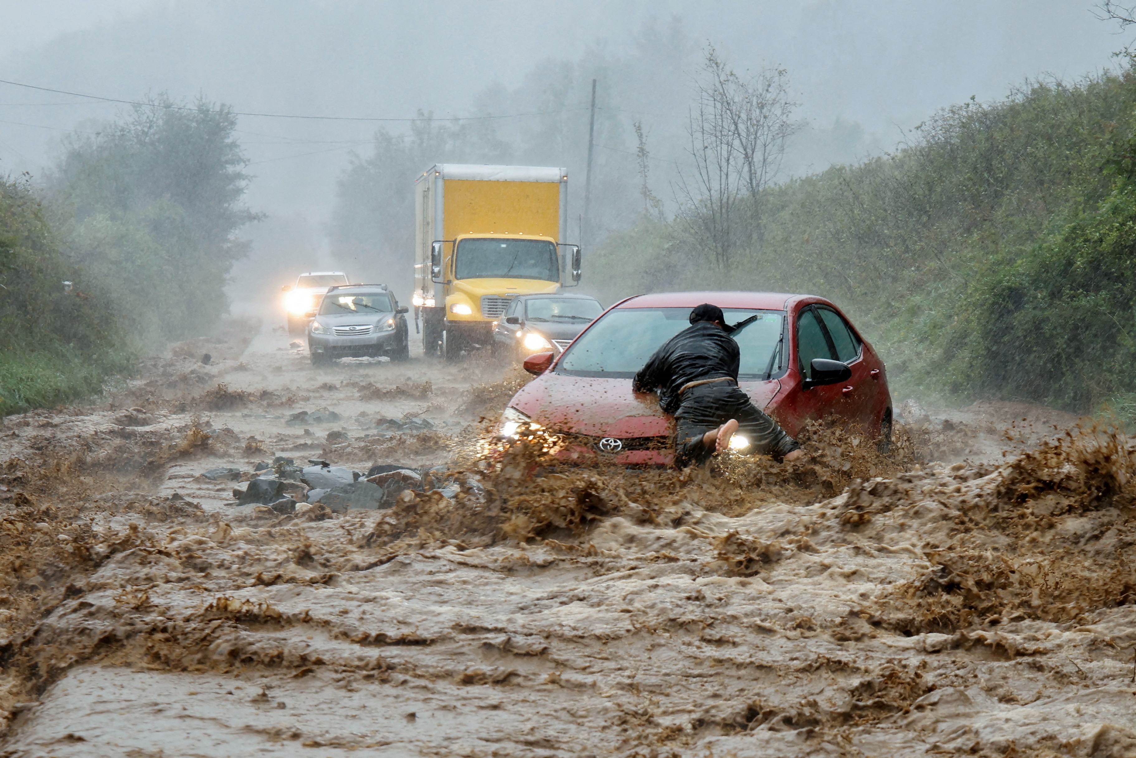 A local resident helps free a car that became stranded in a stretch of flooding road as Tropical Storm Helene strikes, on the outskirts of Boone, North Carolina, U.S. September 27, 2024