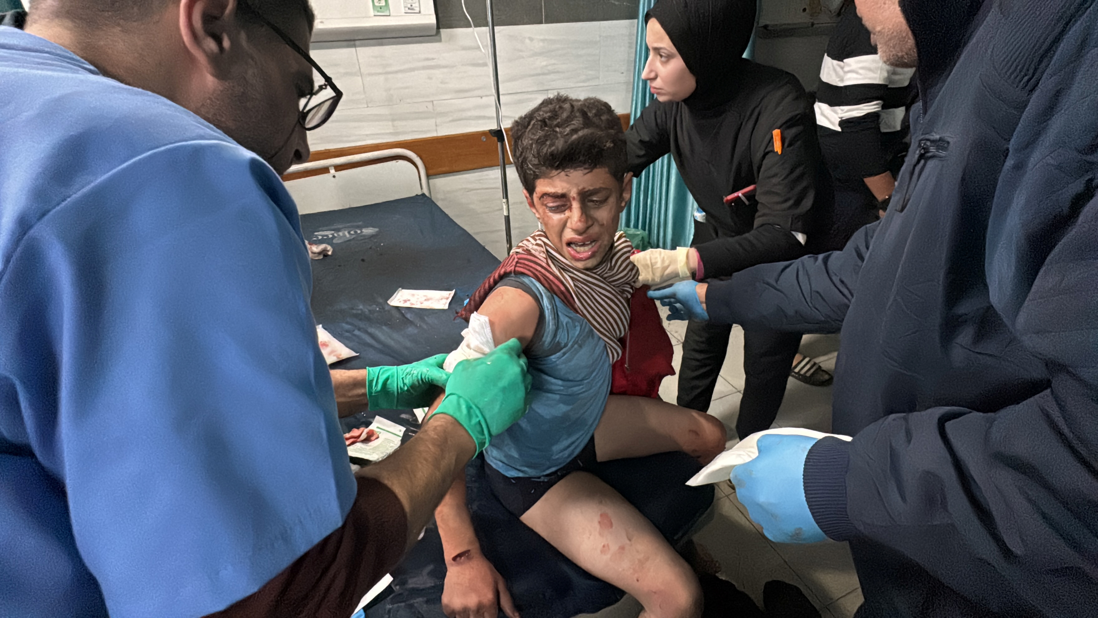 People and medics assist a wounded Palestinian child at Kamal Adwan hospital