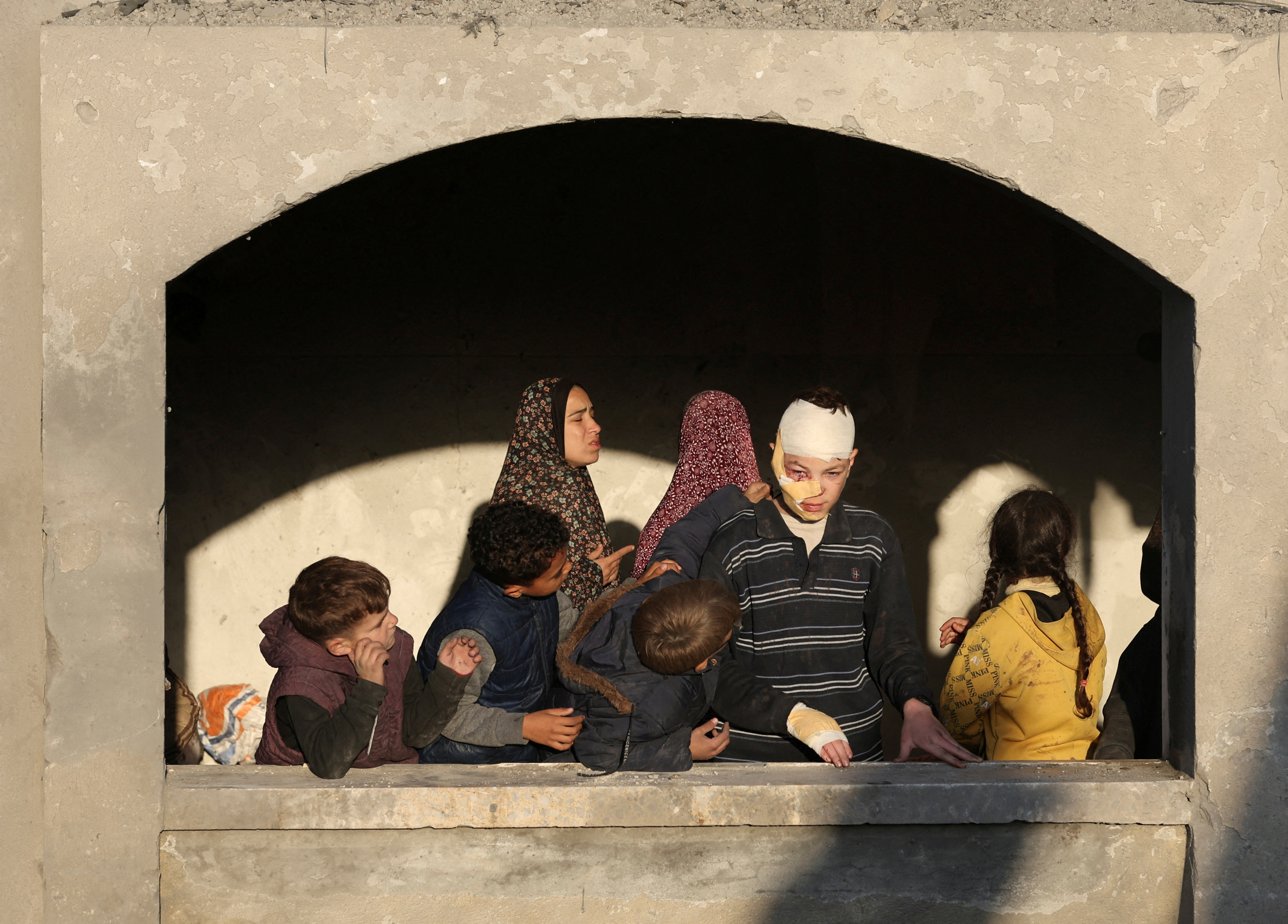 Palestinians look on, at the site of an Israeli strike on a house