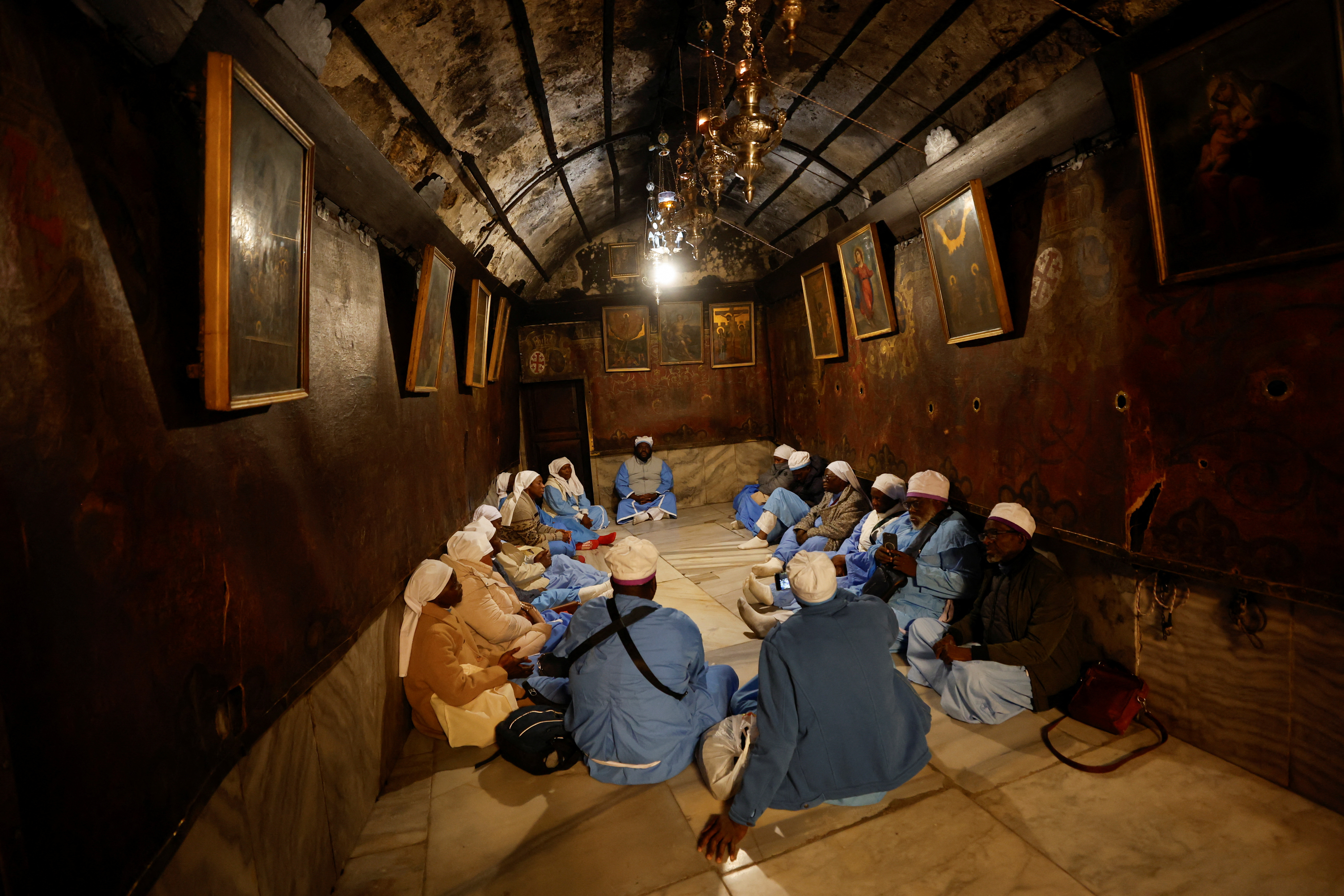 People sit at the Church of the Nativity ahead of the arrival of the Latin Patriarch of Jerusalem, Pierbattista Pizzaballa, in Bethlehem in the Israeli-occupied West Bank December 24