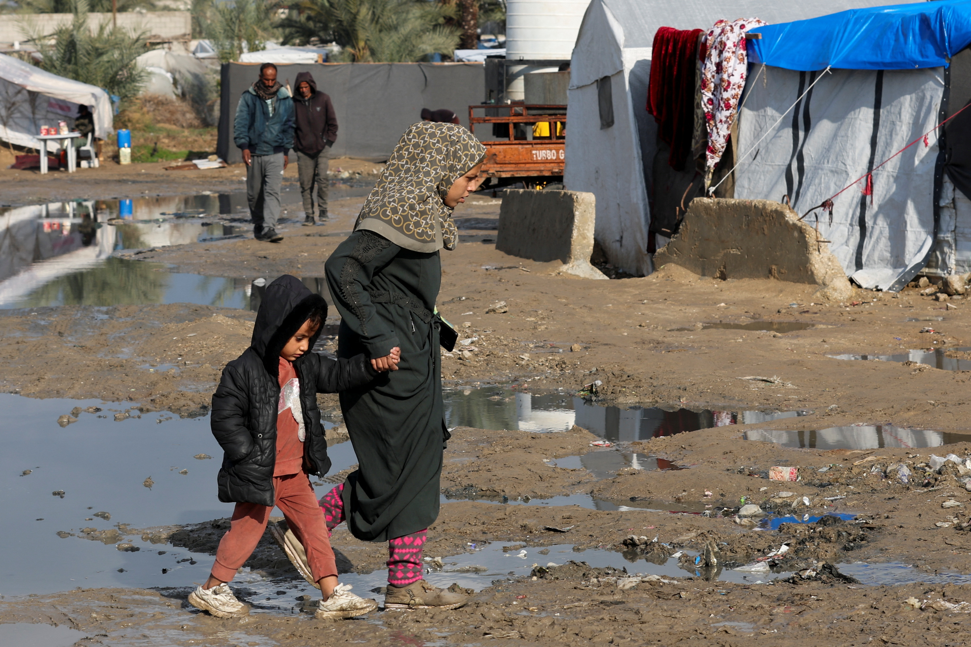 Displaced Palestinian children walk at a tent camp where they shelter, following heavy rains, amid the Israel-Hamas conflict, in Deir Al-Balah, in the central Gaza Strip, December 30