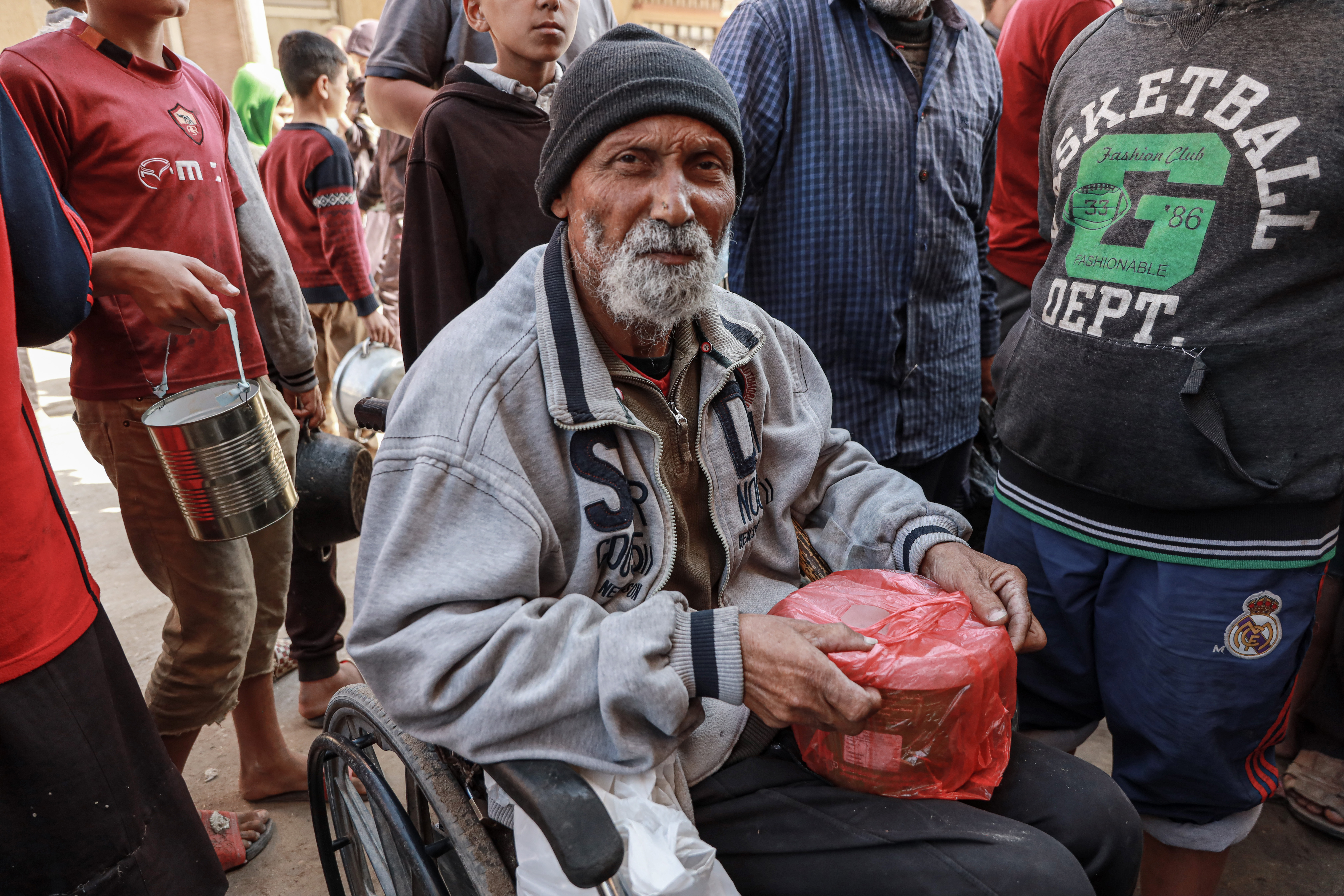 Mohammed Abu Rami comes daily in his wheelchair to receive the only meal for his family from the tekkiyyat in Deir al-Balah. Tekkiyyat is the only source of food for thousands of displaced people in Gaza [Abdelhakim Abu Raish/Al Jazeera]