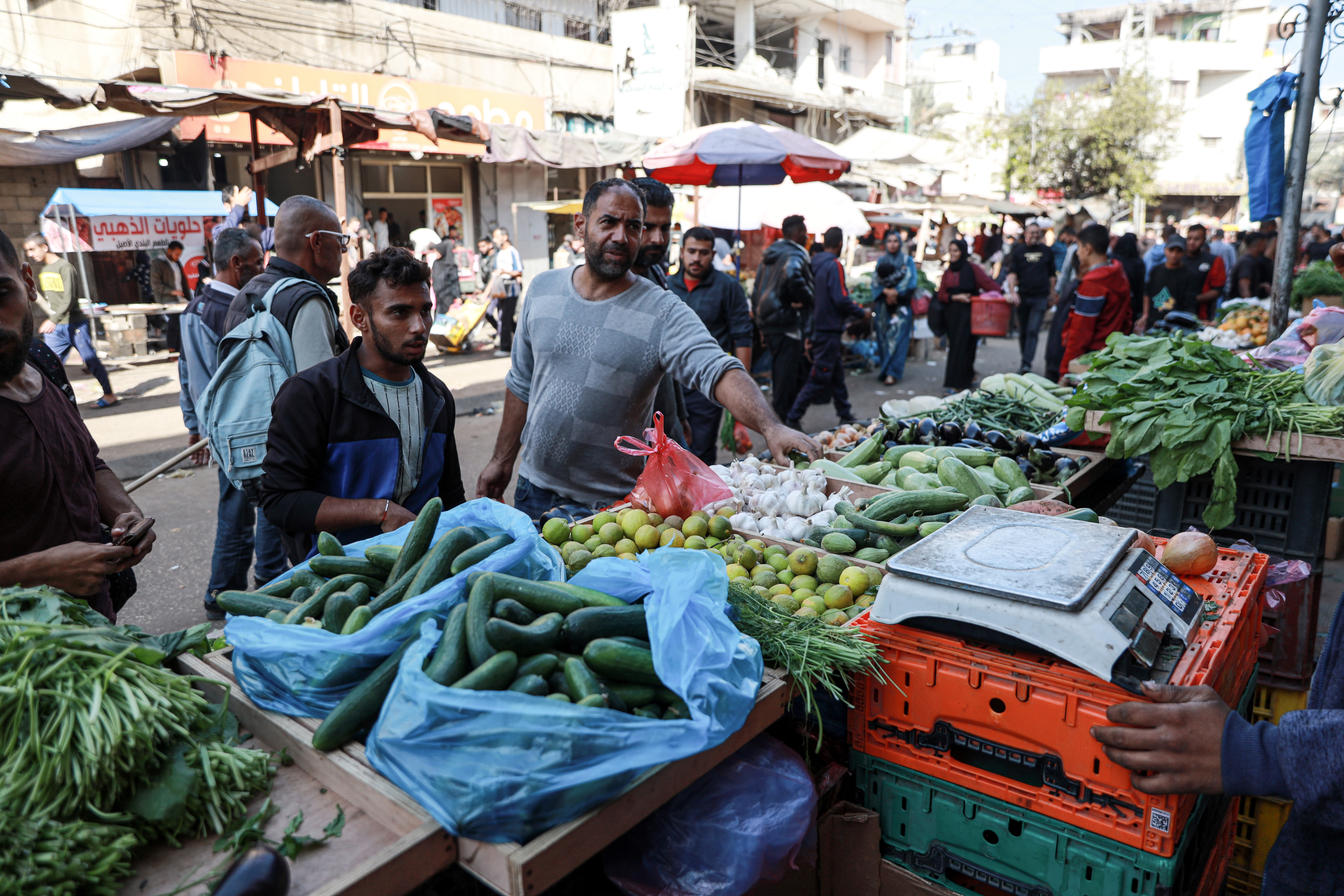 Alaa al-Batniji shops at the local vegetable market in Deir el-Balah [Abdelhakim Abu Riash/Al Jazeera]