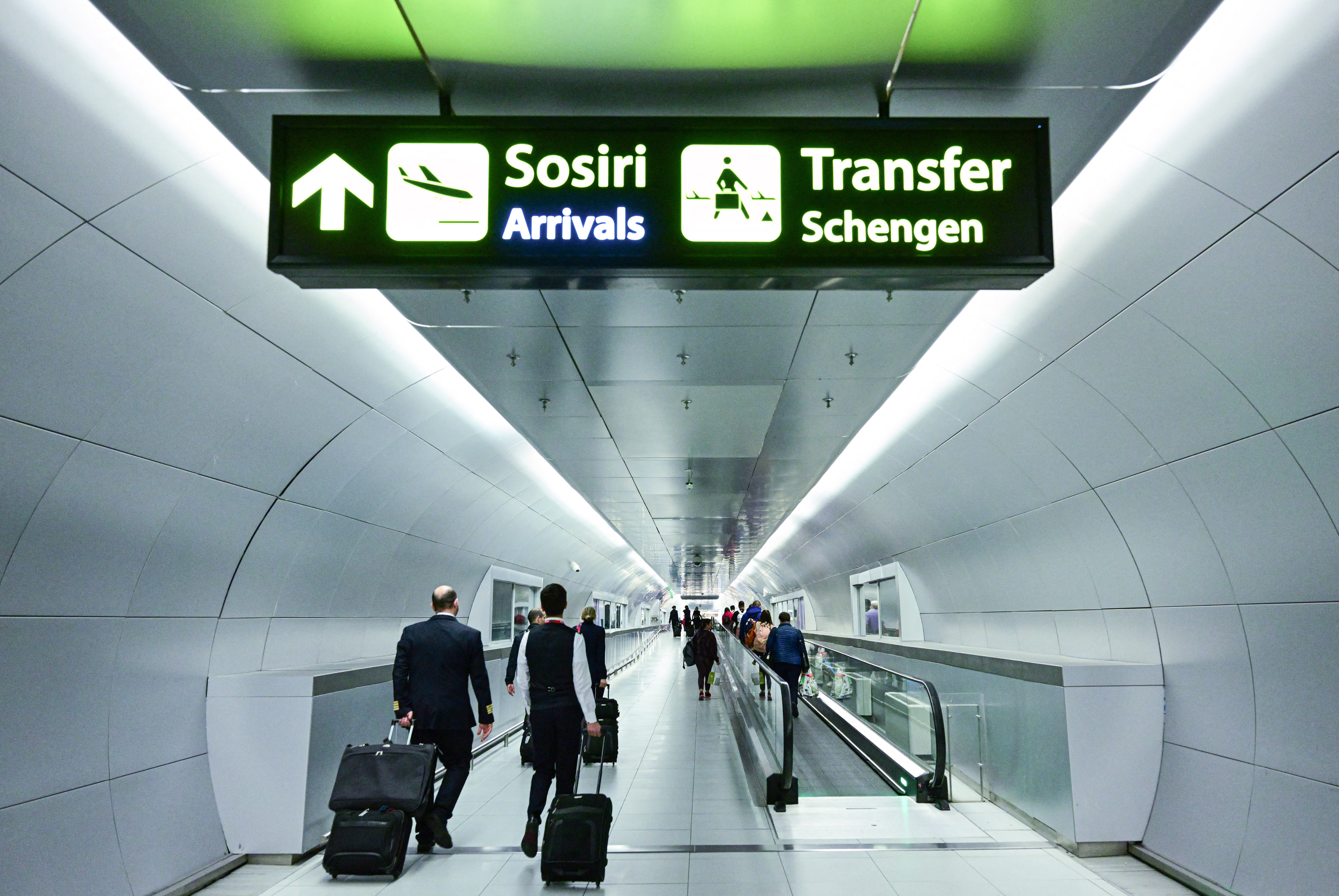 Travellers walk next to newly installed signs pointing to Schengen transfer flights areas, just after Romania’s official entry into the European area of free circulation at Otopeni’s Henri Coanda airport on March 31, 2024
