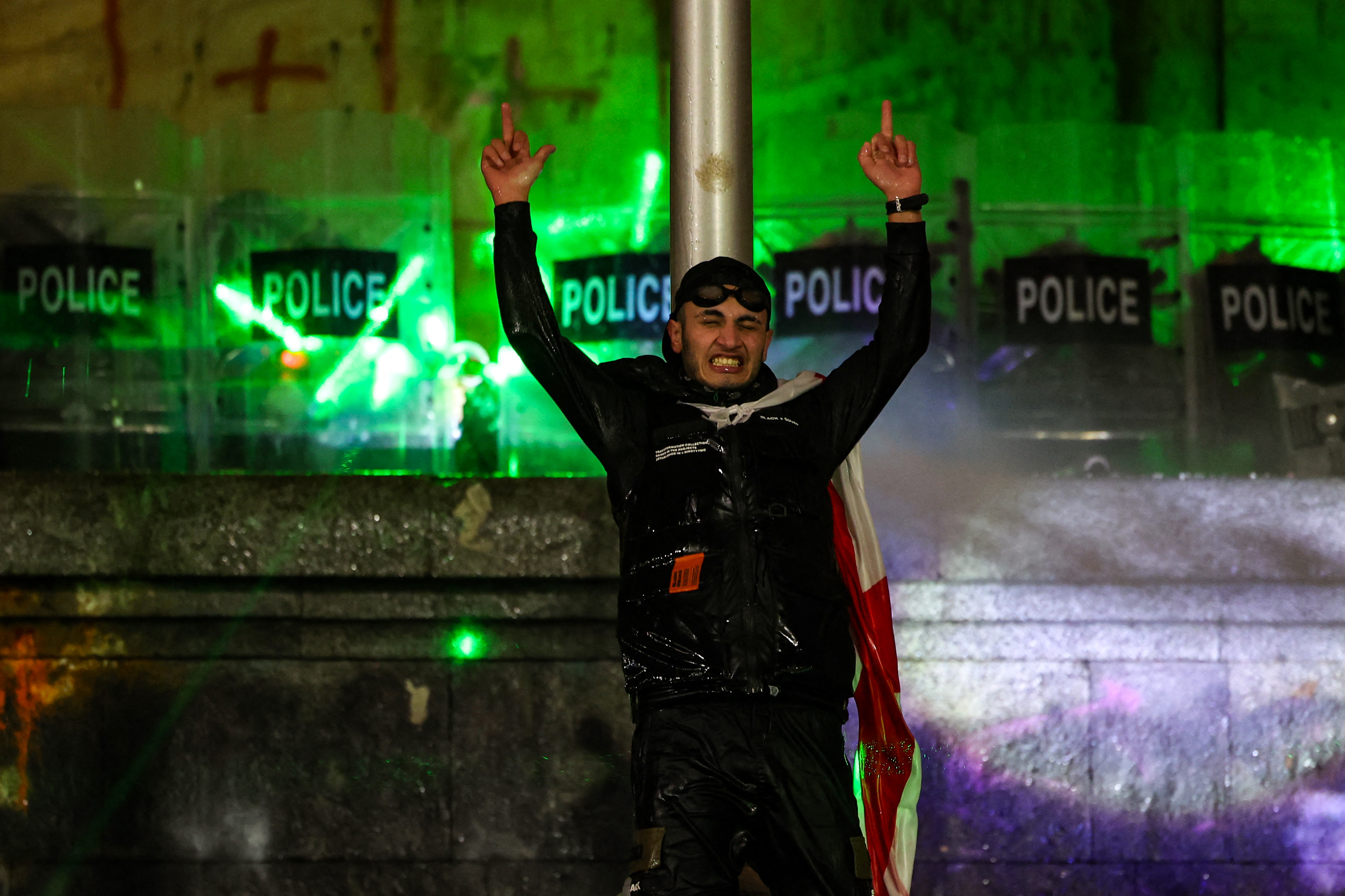 Police form a shield wall and use a water hose while securing the parliament building from protesters during the fifth straight night of demonstrations against the government's postponement of EU accession talks until 2028, in central Tbilisi