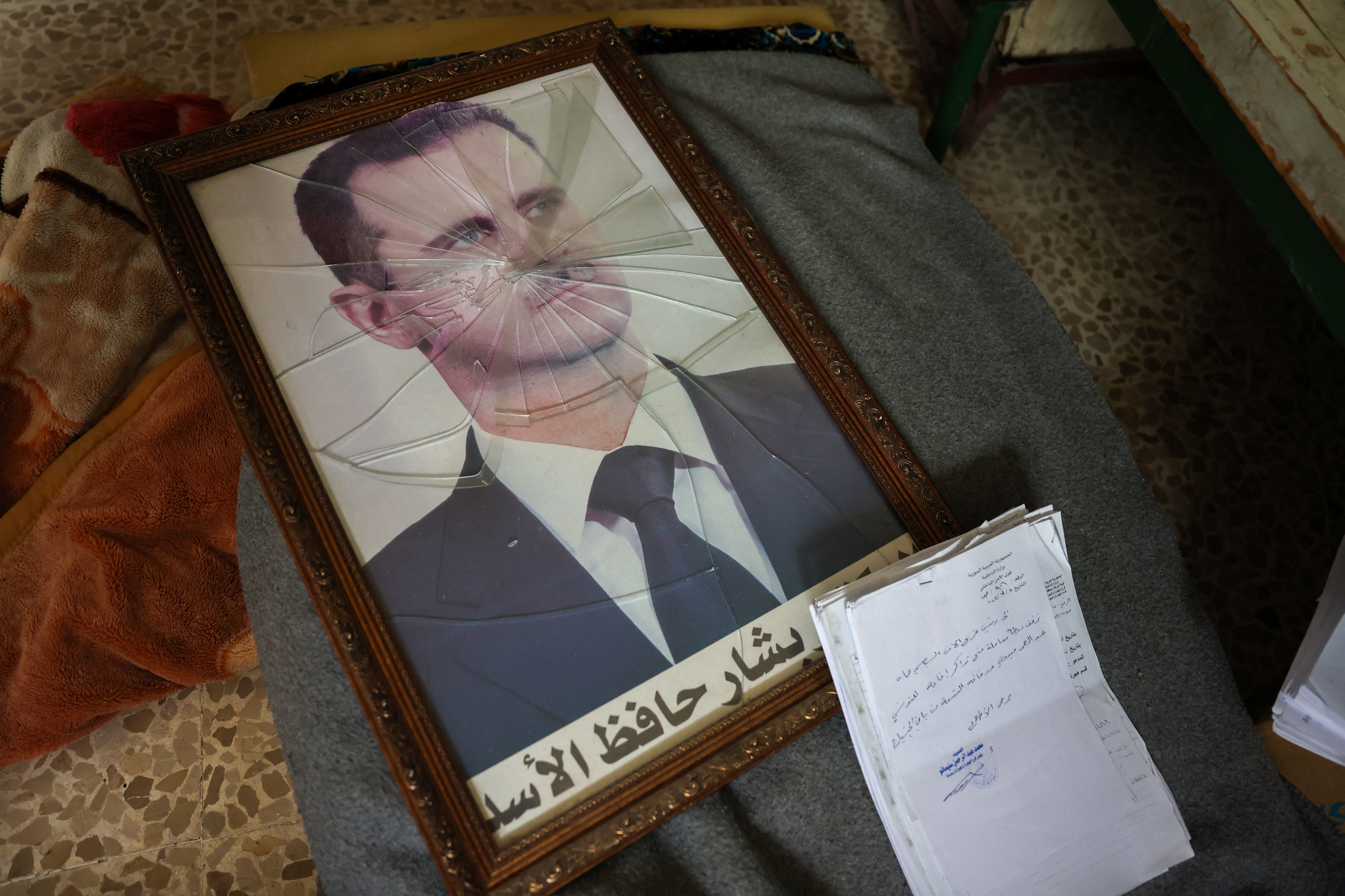 A portrait of Syrian President Bashar al-Assad is pictured with its frame broken, in a Syrian regime's Political Security Branch facility on the outskirts of the central city of Hama,