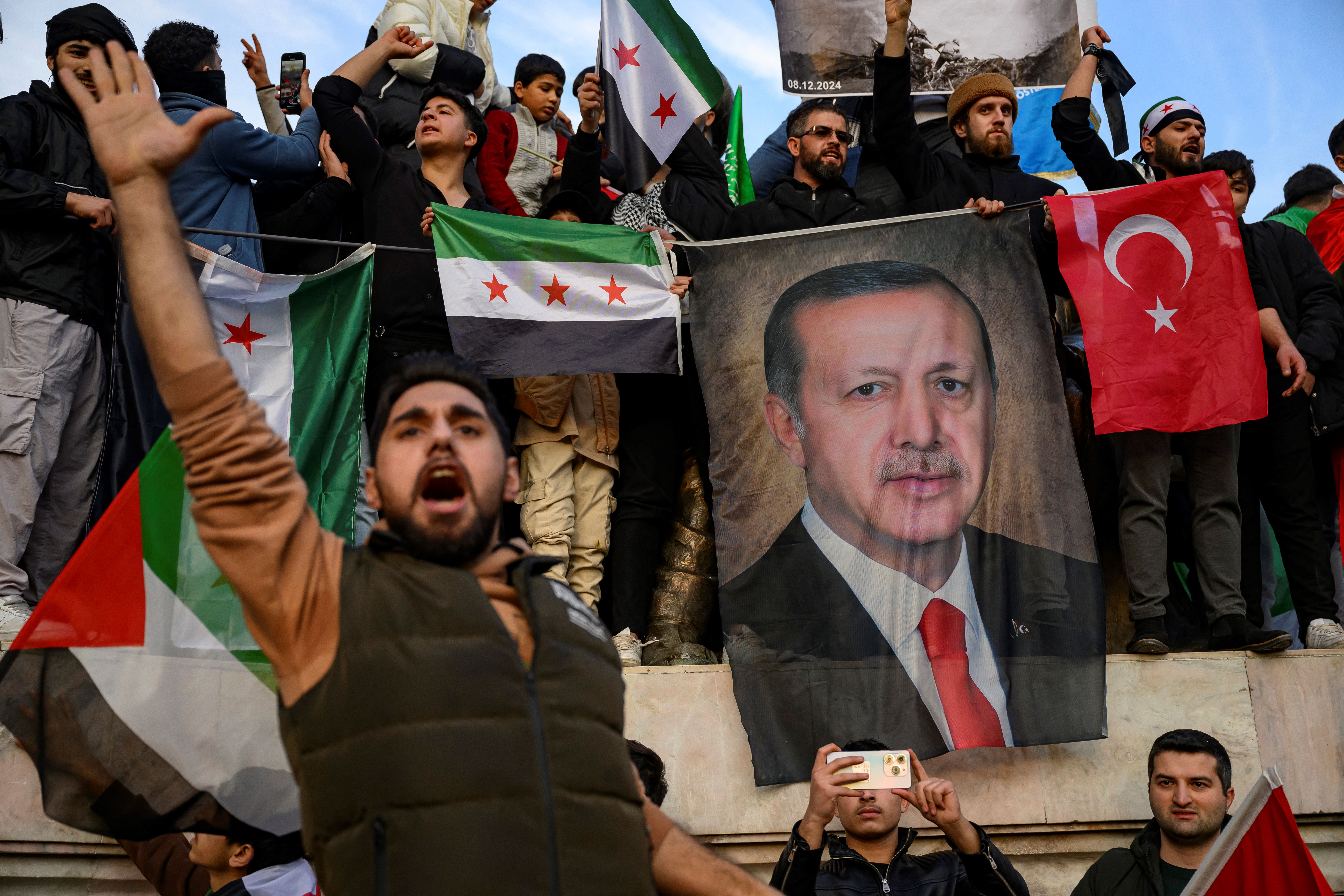 People hold a banner featuring Turkish President Recep Tayyip Erdogan as Syrians and their supporters gather in Istanbul to celebrate the fall of Syrian leader Bashar al-Assad