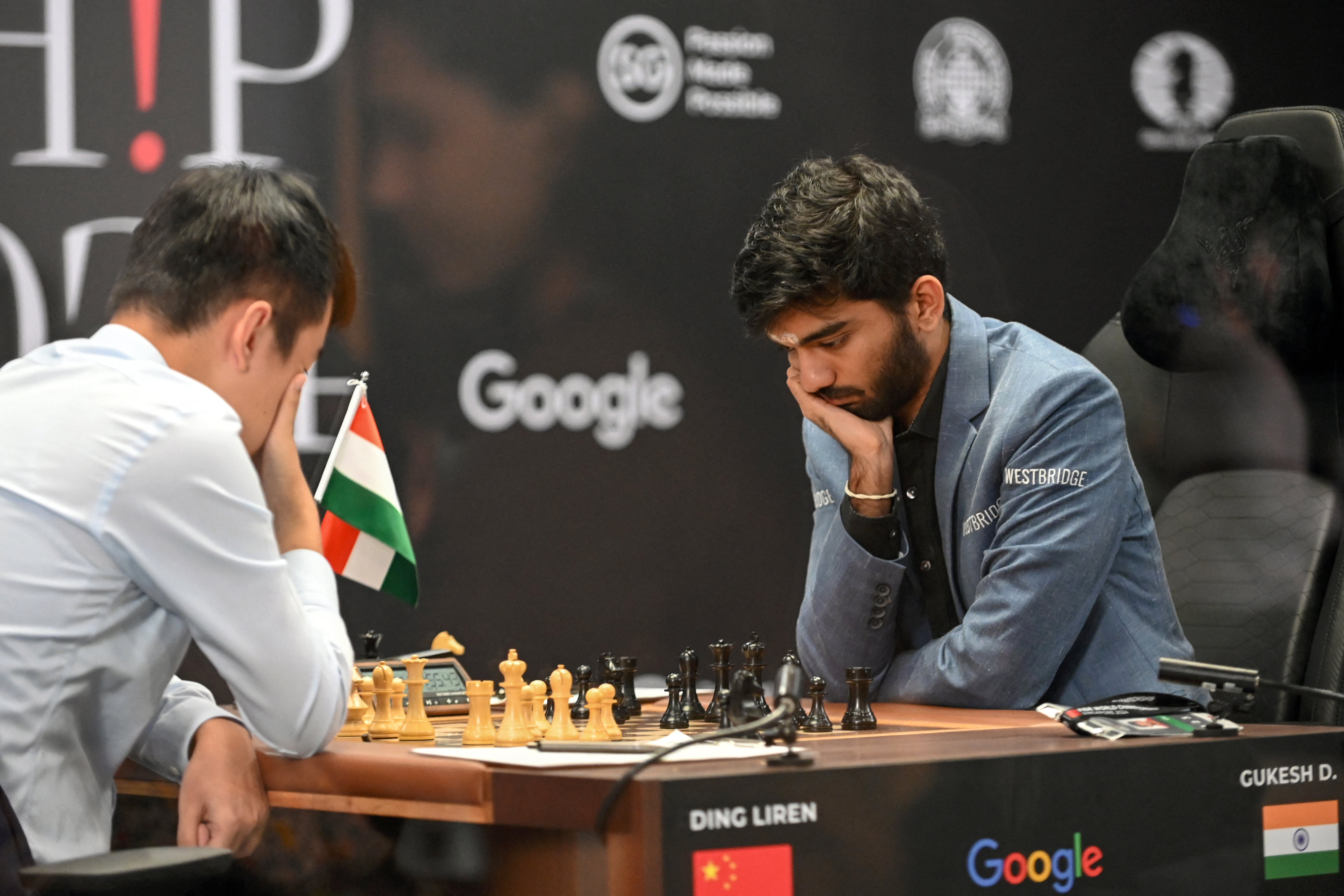 China's chess grandmaster Ding Liren (L) and India's grandmaster Gukesh Dommaraju (R) compete in game 14 of the 2024 FIDE World Championship in Singapore on December 12, 2024.