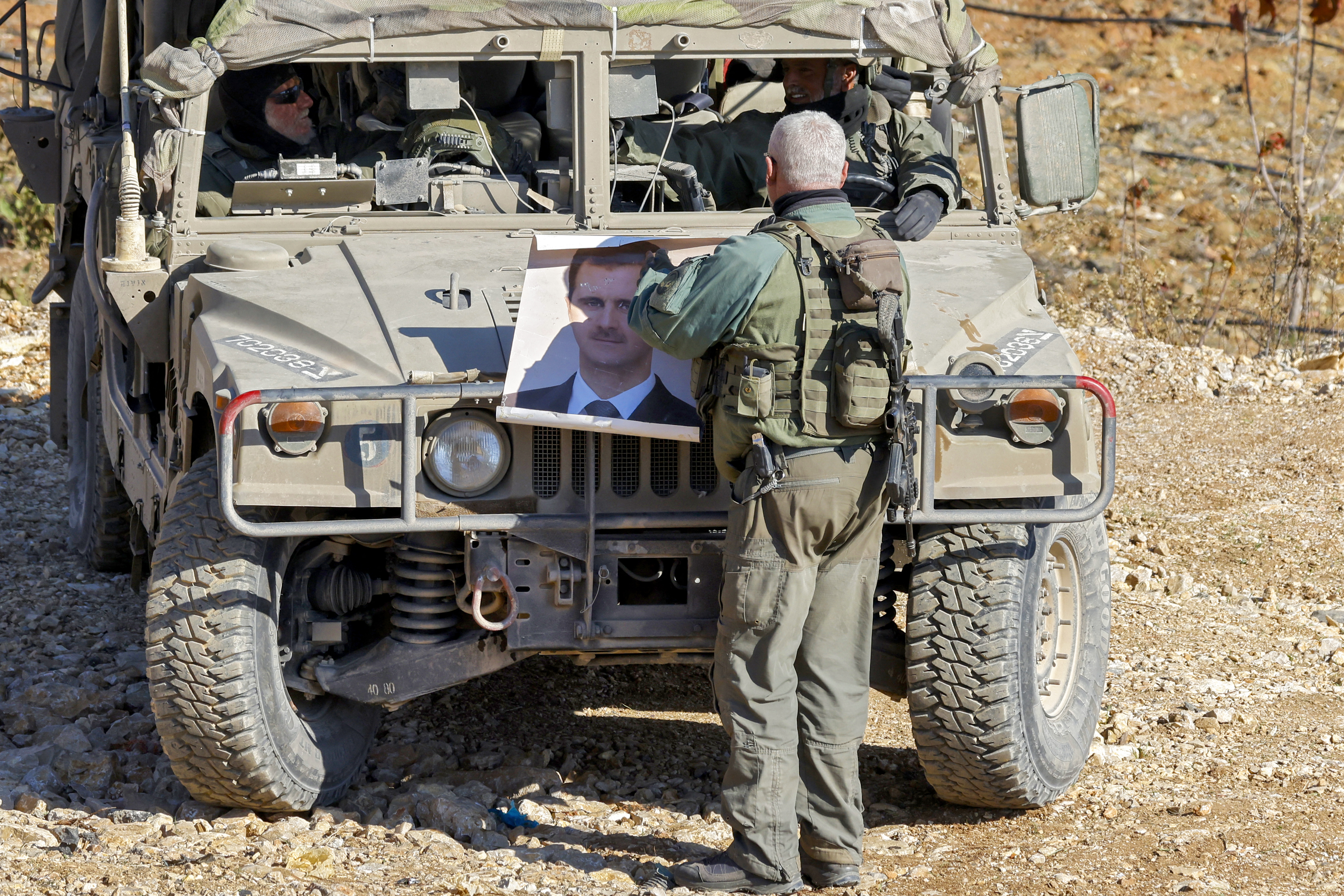 An Israeli army soldier holds a portrait of Bashar al-Assad by a vehicle near the Druze village of Majdal Shams in the occupied Golan Heights