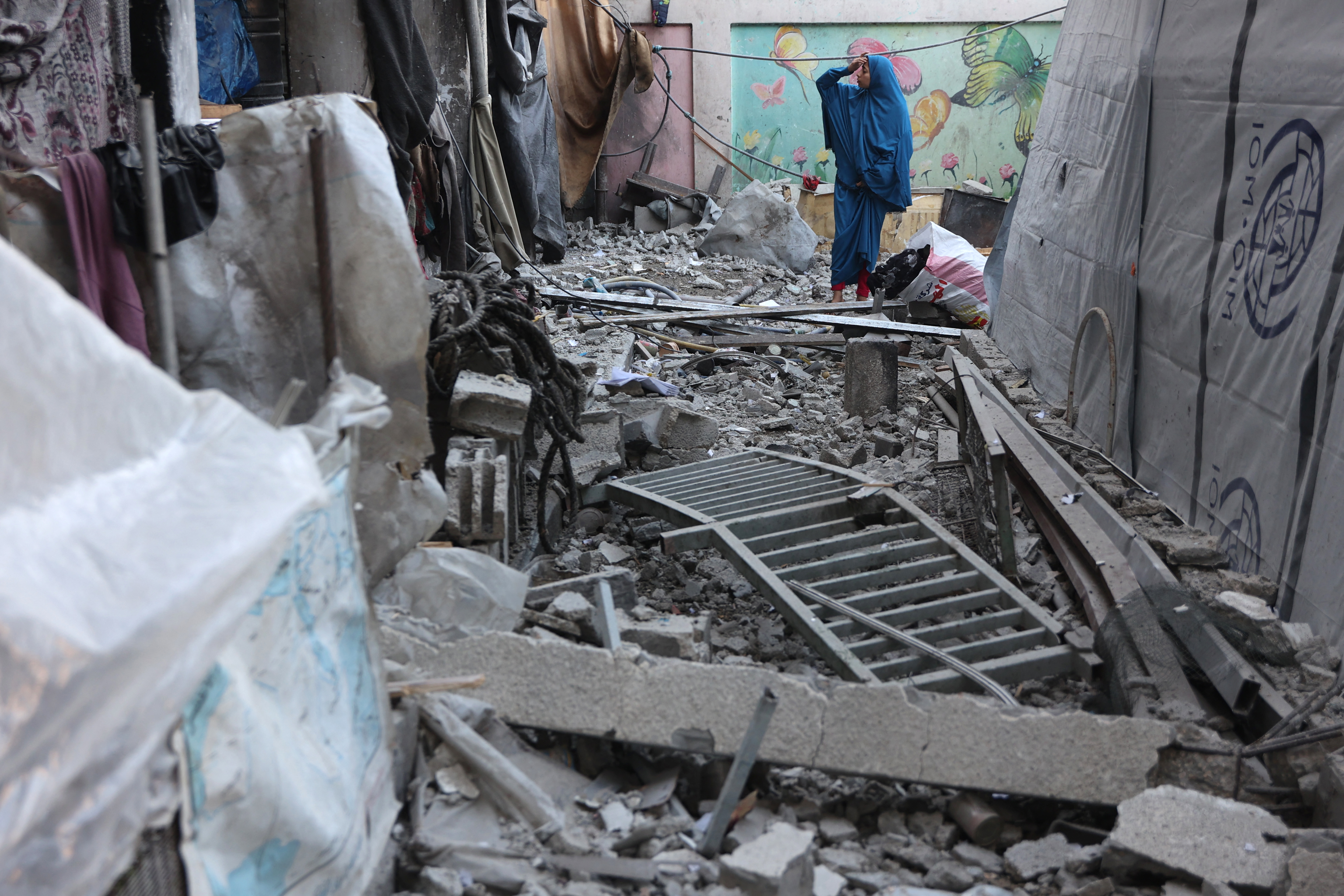 A woman inspects the damage at the site of an Israeli strike that targeted the Musa bin Nusayr School in the Al-Daraj neighbourhood in Gaza City on December 22