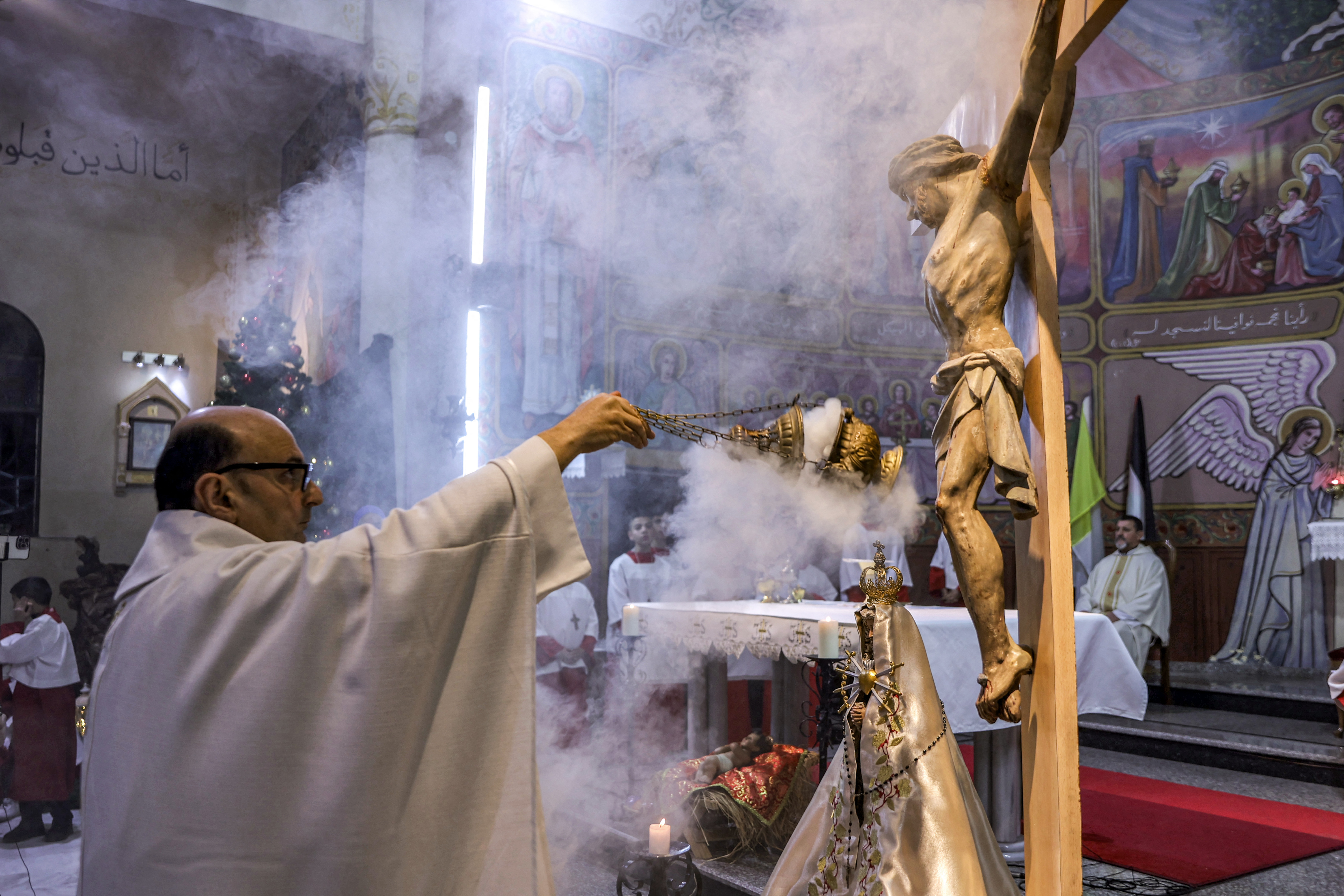 Father Gabriel Romanelli, Parish Priest of the Roman Catholic Church of the Holy Family Church, censes before a crucifix during Christmas Eve mass at the church in the Zaytoun neighbourhood of Gaza City on December 24
