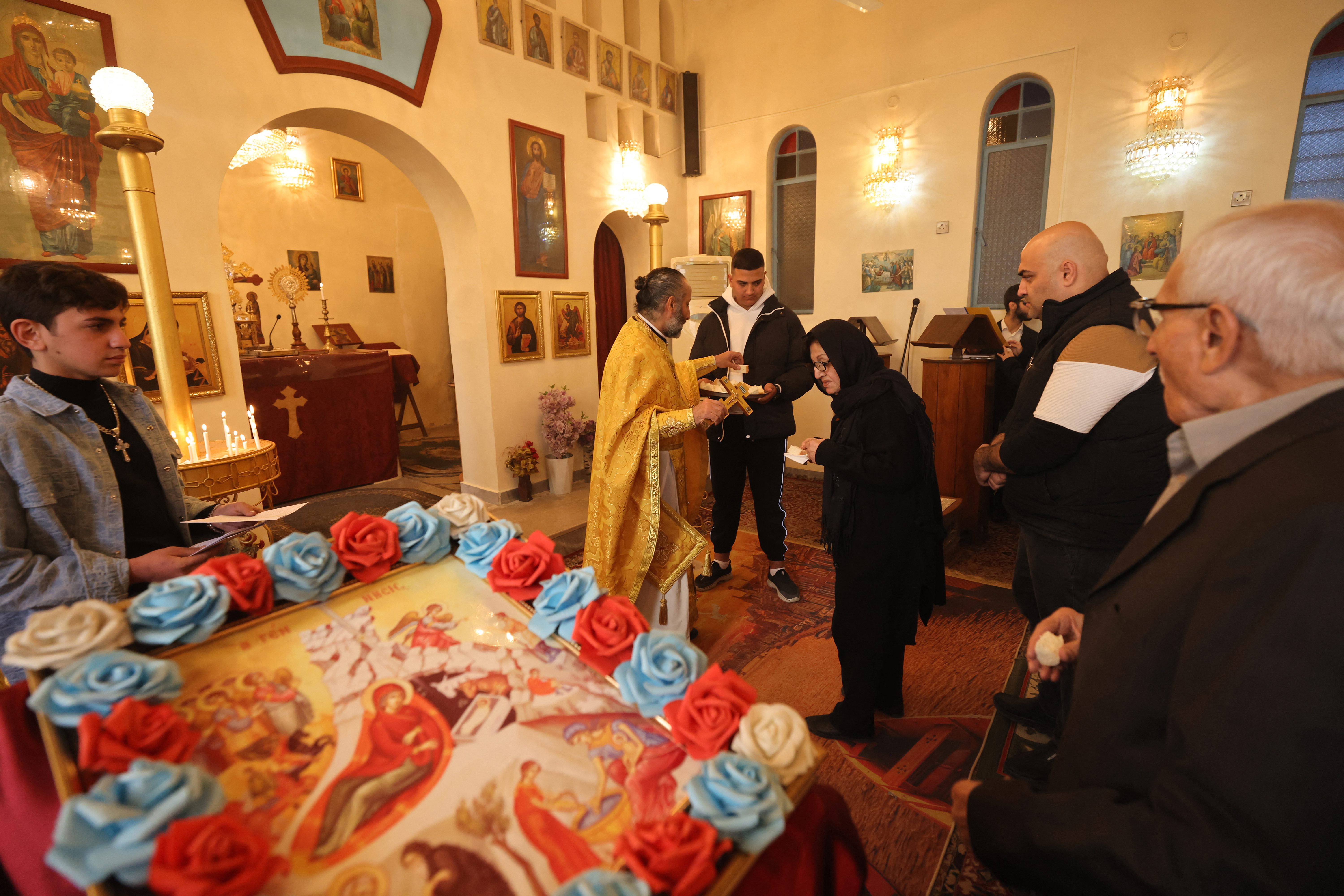 Father Younan Ibrahim hands out communion bread during the Christmas morning Mass at the Greek Orthodox Church of St Andrew in Baghdad on December 25