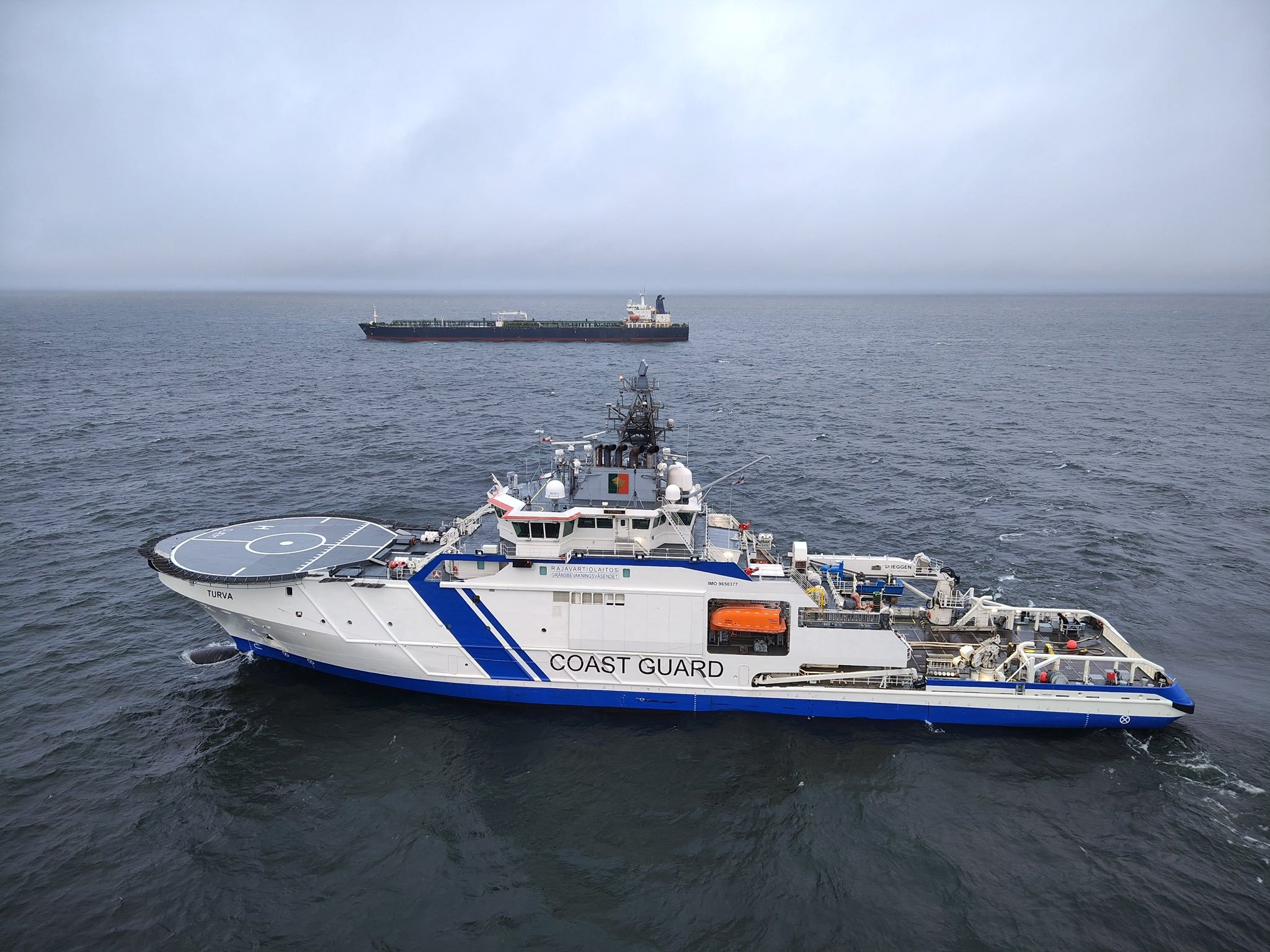 This handout picture released by The Finnish Border Guard on December 26, 2024 shows a Finnish Border Guard's ship Turva (front) and the oil tanker Eagle S on the sea near Porkkalanniemi. - Finnish authorities said on December 26, 2024 that they were investigating an oil tanker that sailed from a Russian port for the "sabotage" of a power cable linking Finland and Estonia that was damaged the previous day.