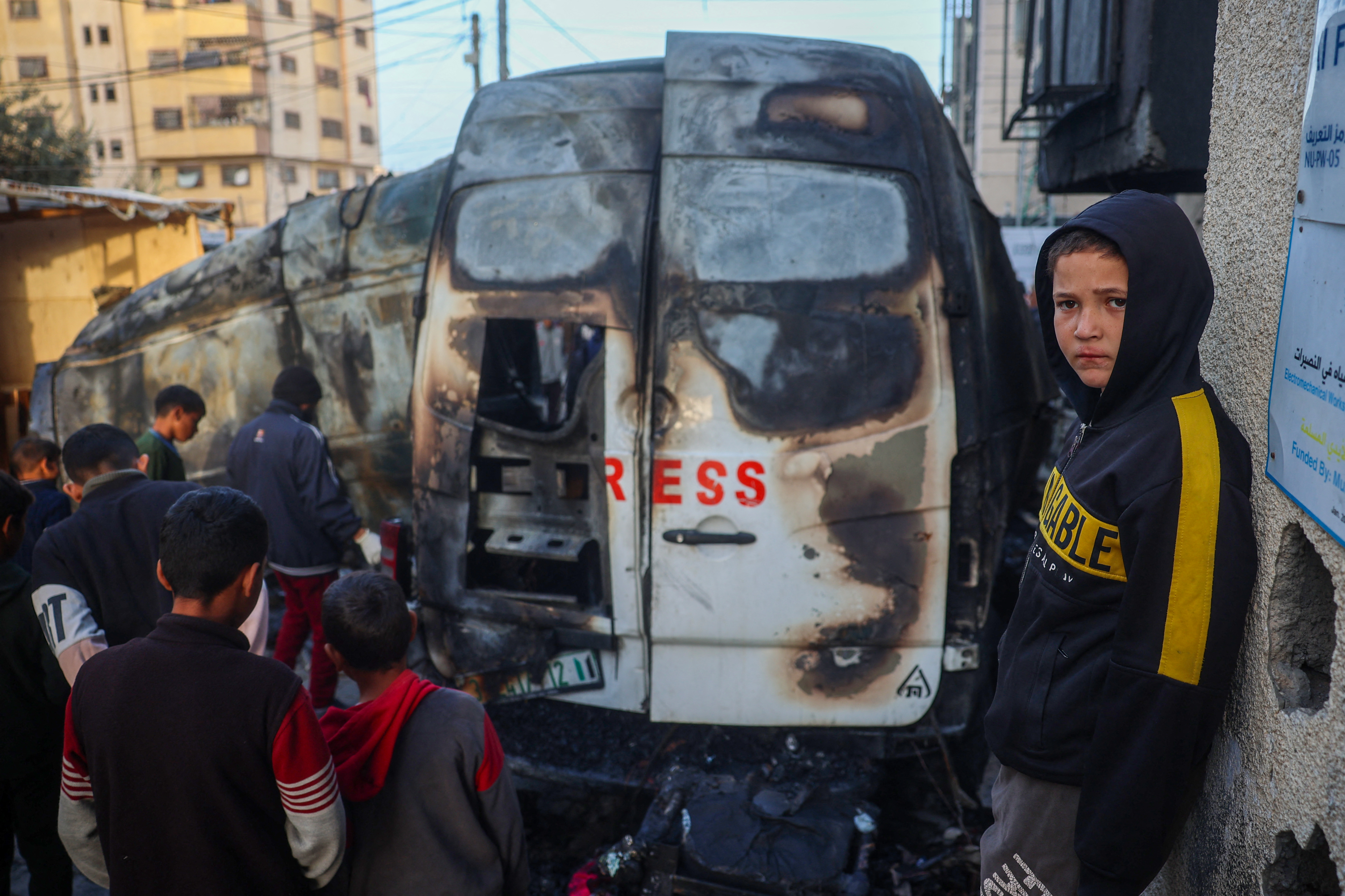 Children check the site of an Israeli strike on a broadcast truck, in the Nuseirat refugee camp in the central Gaza Strip, on December 26