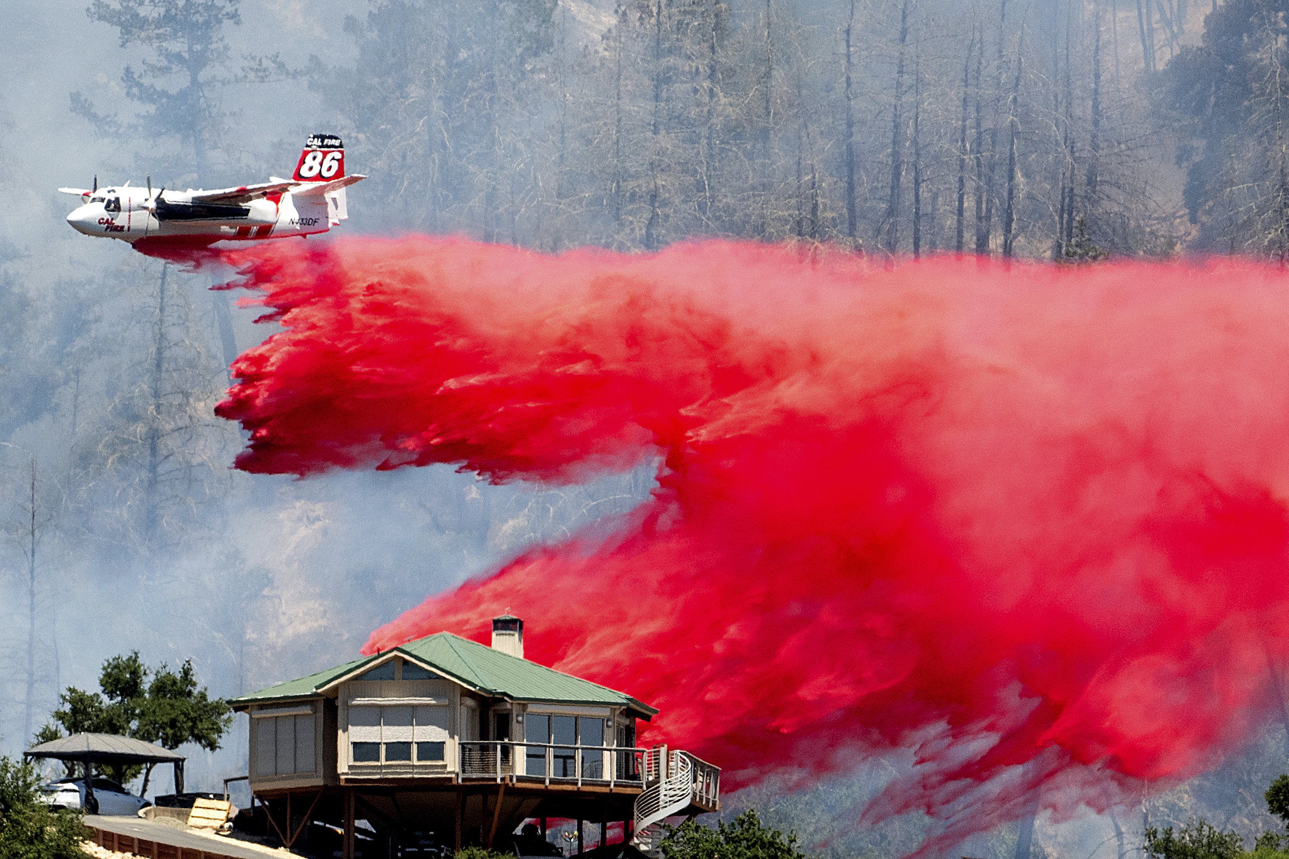 An air tanker drops retardant behind a home while battling the Toll Fire near Calistoga, Calif., on Tuesday, July 2, 2024