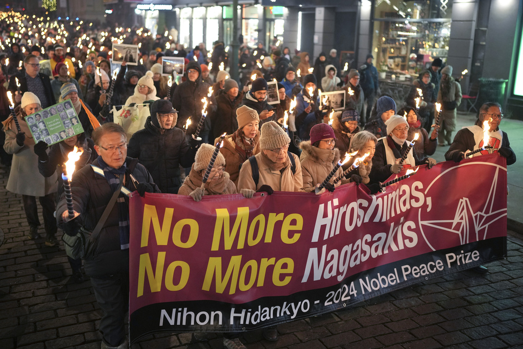 people hold a banner that says no more Hiroshimas, no more Nagasakis