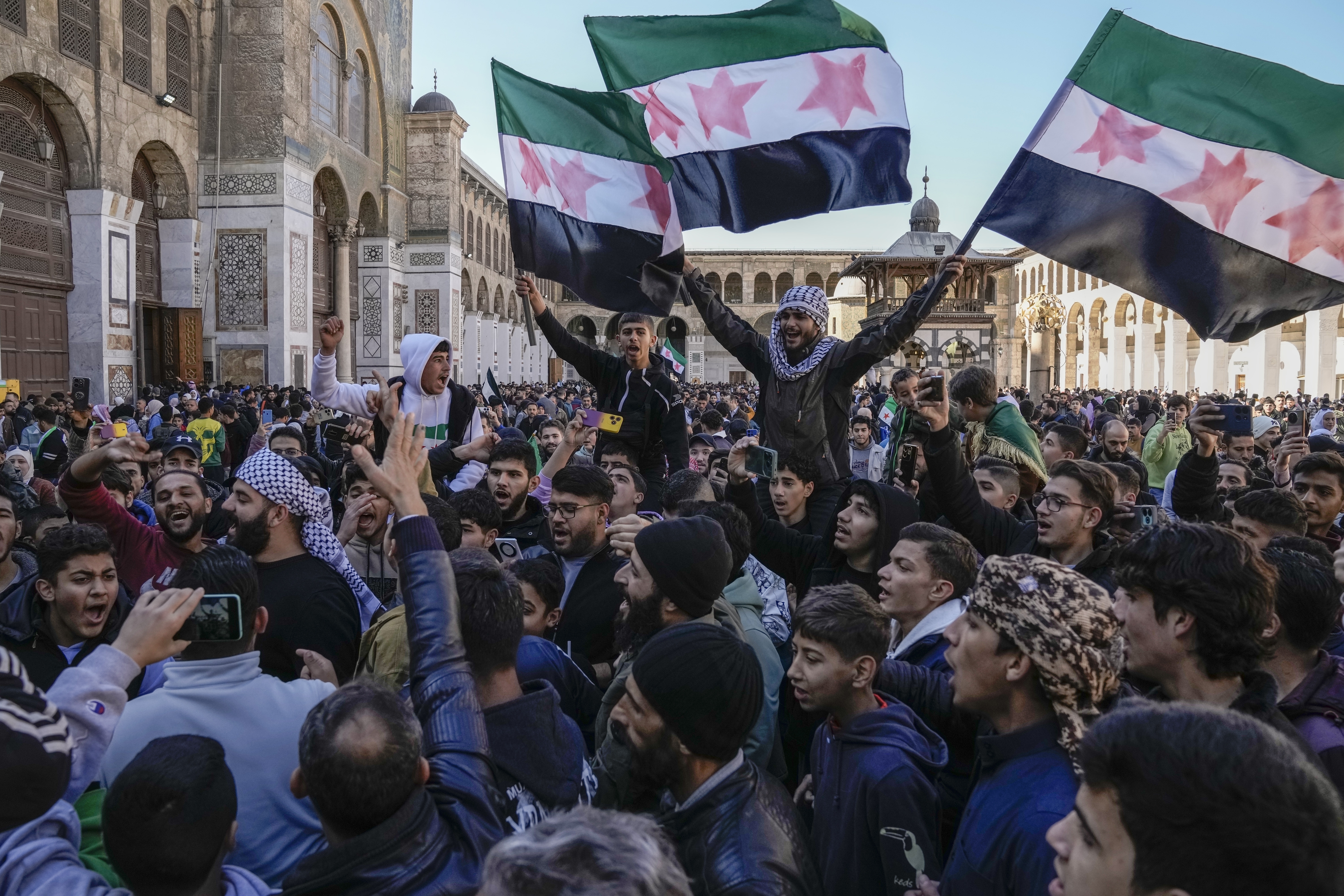 People chant slogans and wave the new Syrian flag in Damascus