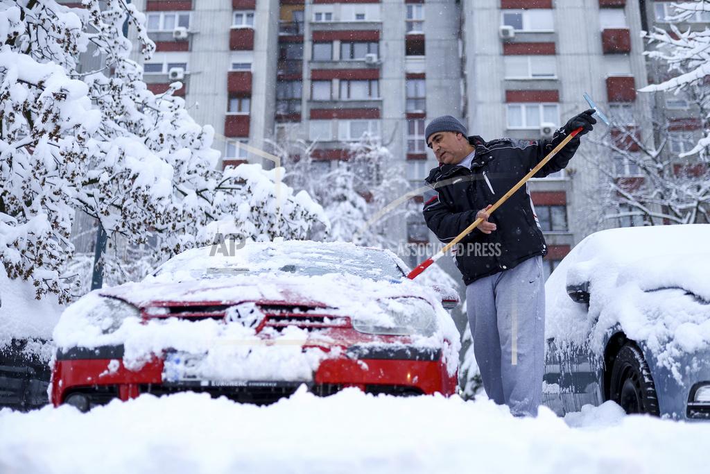 A man cleans snow of his car during heavy snowfall in Sarajevo, Bosnia, Tuesday, Dec. 24, 2024. (AP Photo/Armin Durgut)