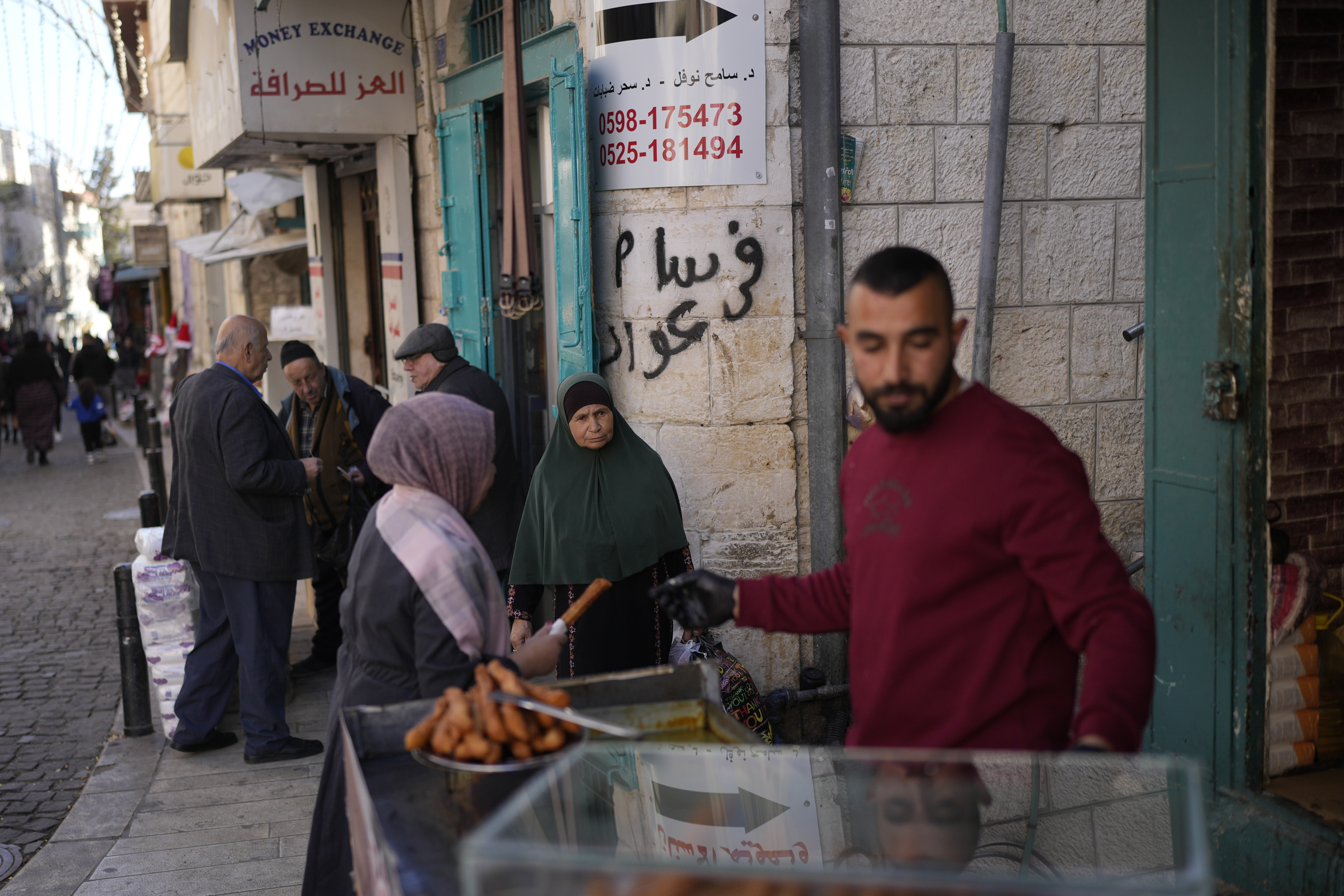 A woman buys street food near the Church of the Nativity, traditionally believed to be the birthplace of Jesus, on Christmas Eve, in the West Bank city of Bethlehem, Tuesday, Dec. 24
