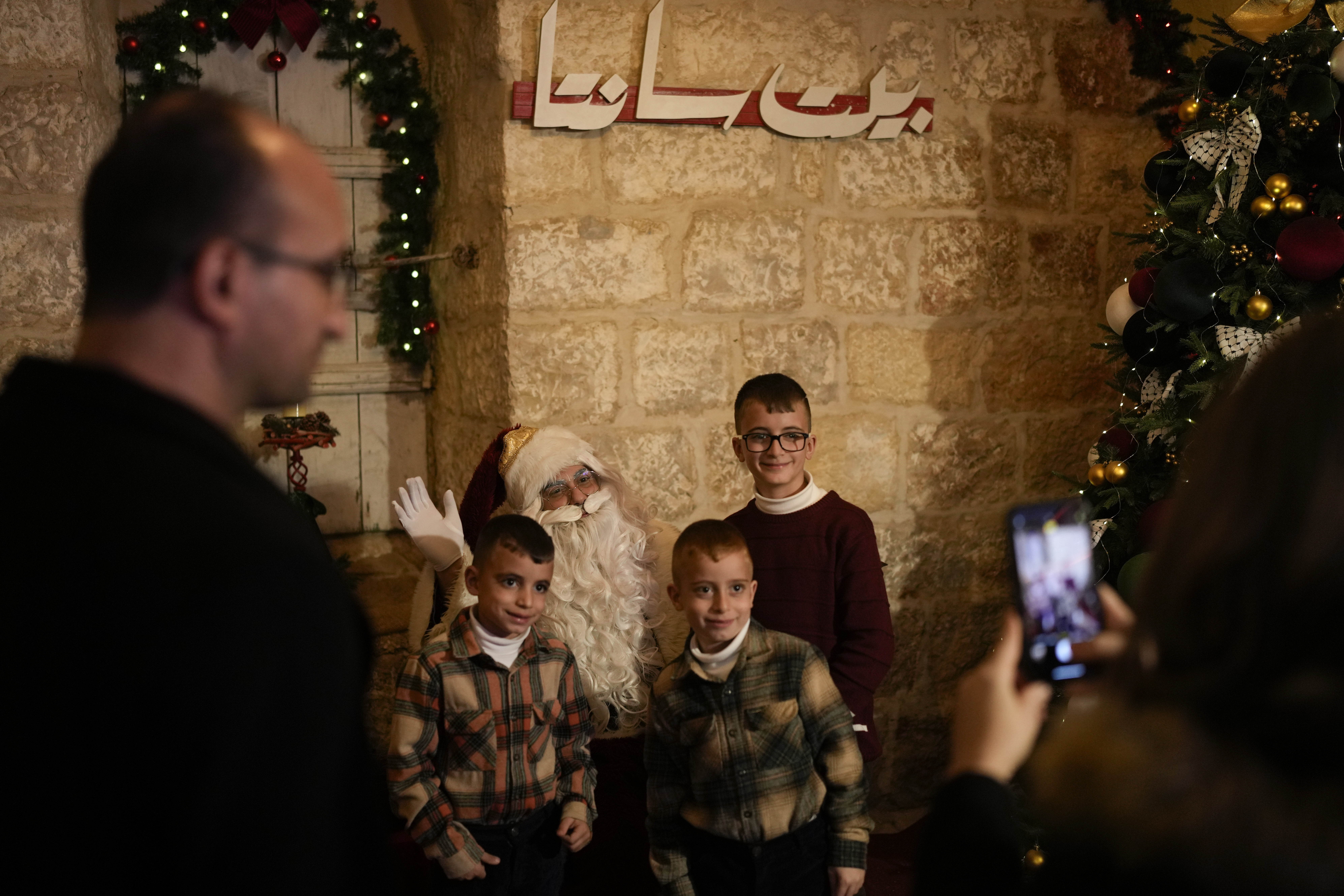 Children pose for a photo with a man dressed as Santa Claus near the Church of the Nativity, traditionally believed to be the birthplace of Jesus, on Christmas Eve, in the West Bank city of Bethlehem, Tuesday, Dec. 24