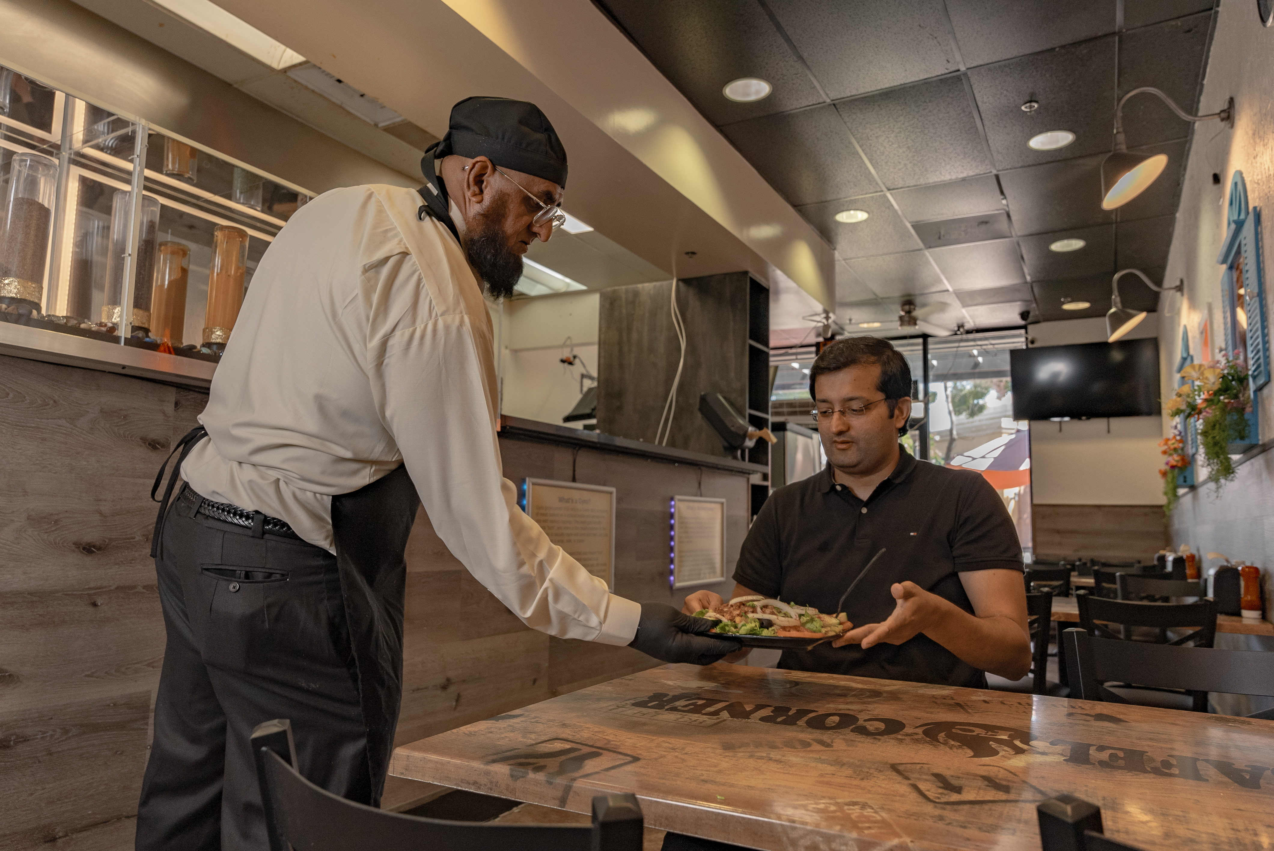 Sajad Shakoor serving food to a customer at his restaurant