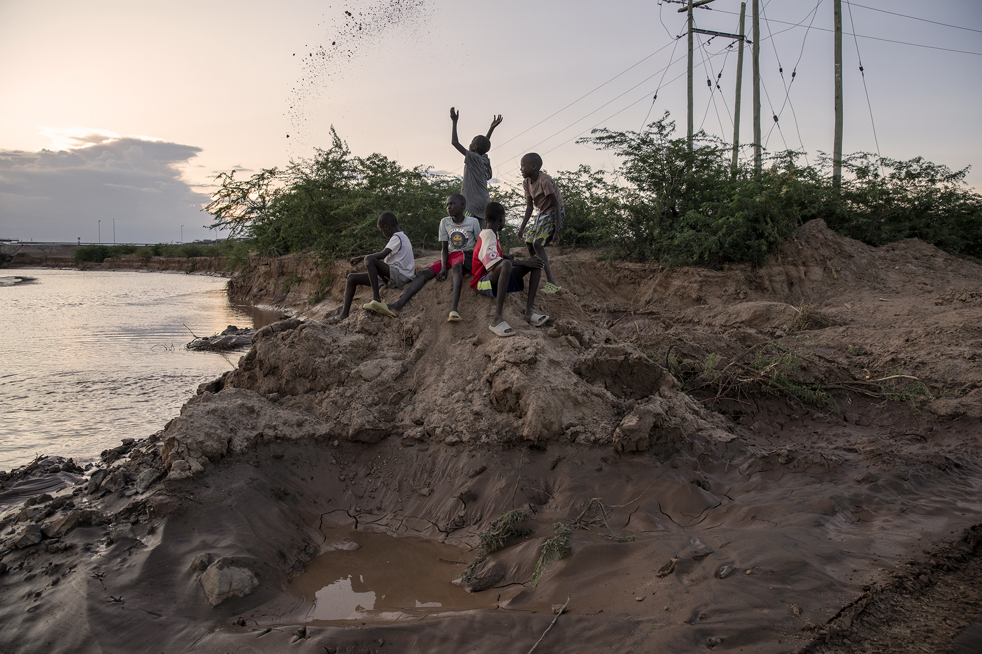 Children play with mud on the bank of the dried Kawalasee River in Lodwar, northwest Kenya on October 19, 2024. Kenya's rivers are drying up rapidly, with low rainfall and global warming being among the main causes of this phenomenon. [Alessio Paduano/Al Jazeera]