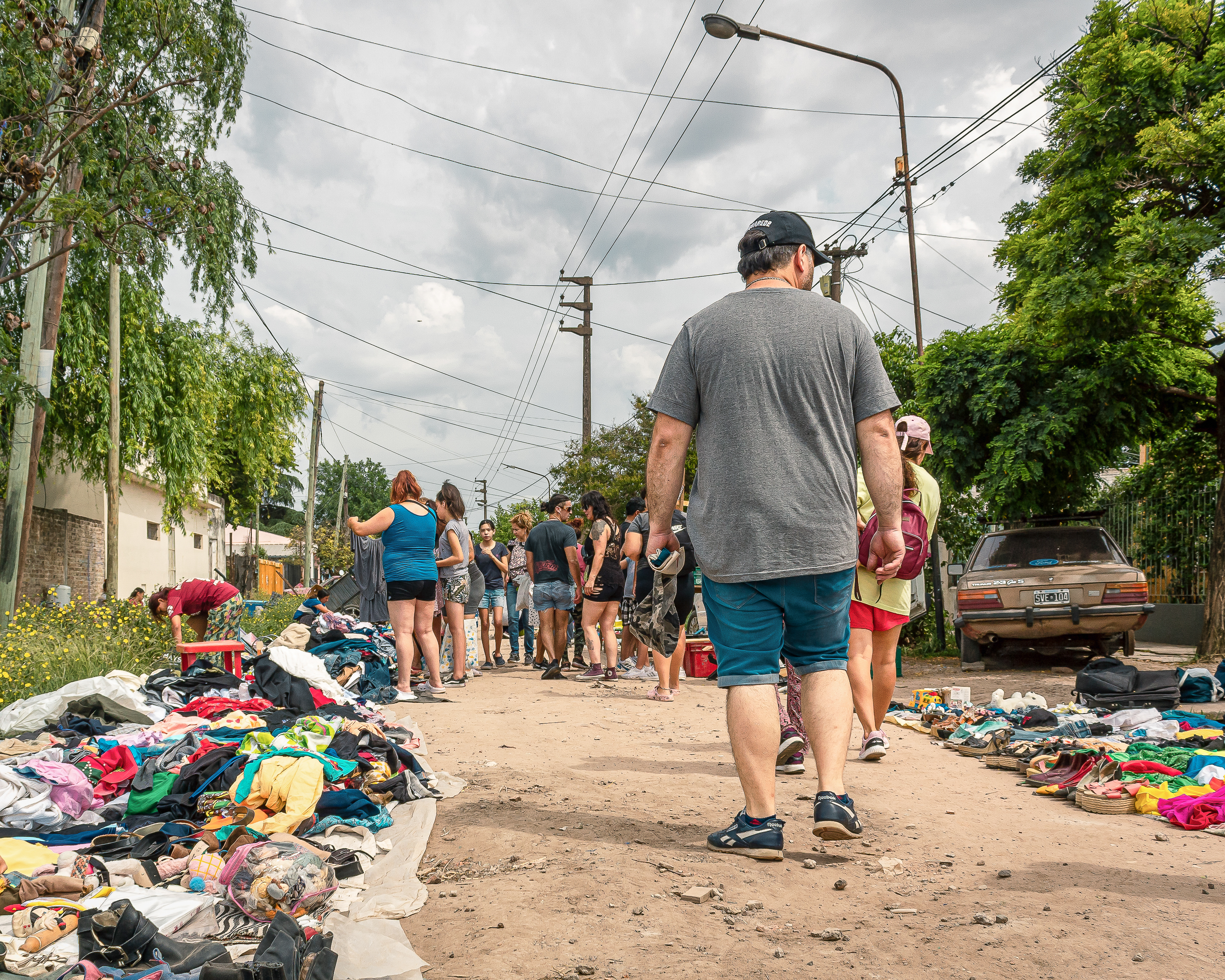 A man walks through an informal clothing market on a dirt road in Argentina.