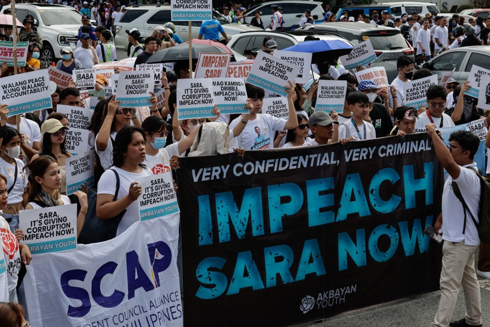 Protesters hold signs calling for the impeachment of Philippine Vice President Sara Duterte during a rally.