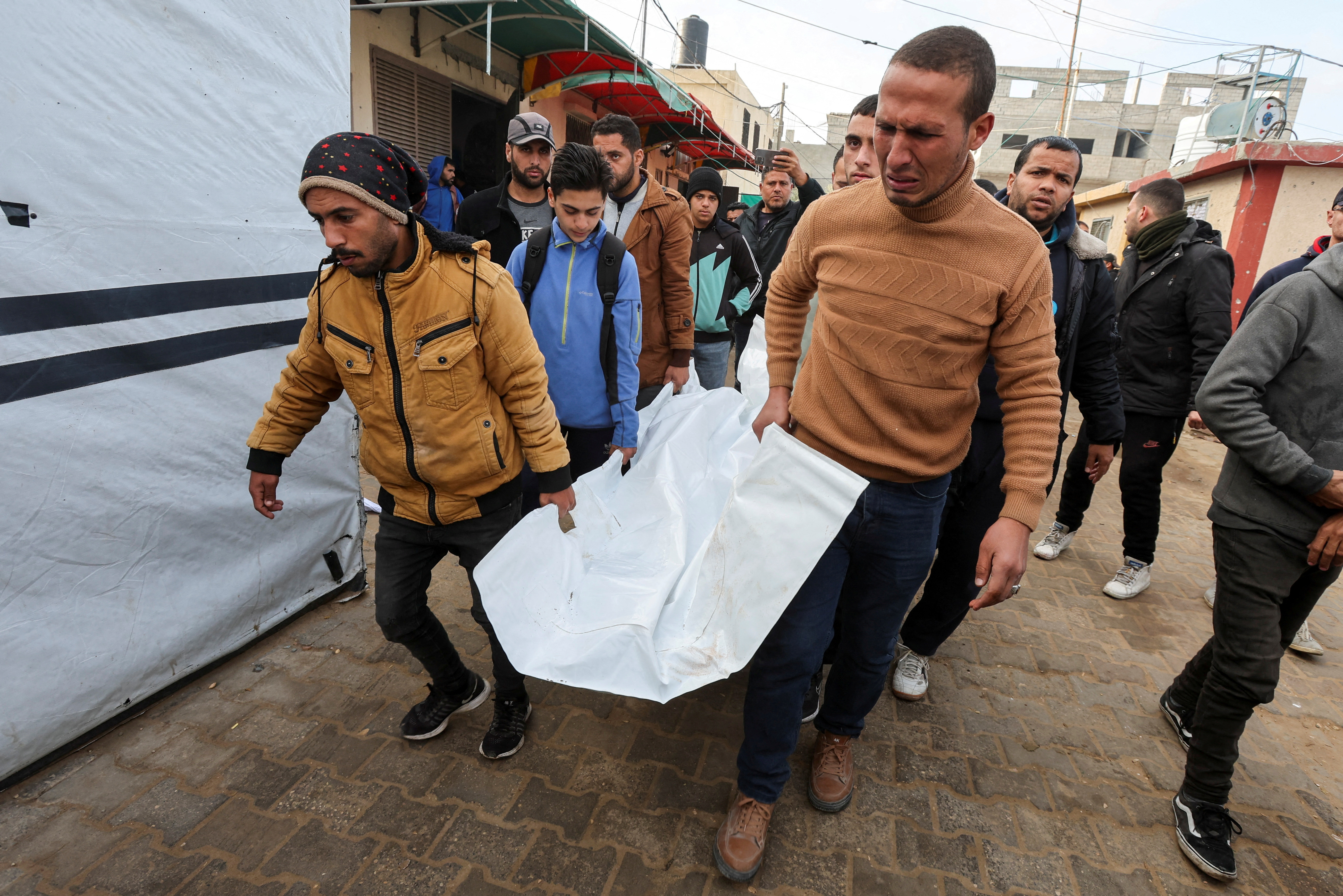 Palestinians carry a shrouded dead body