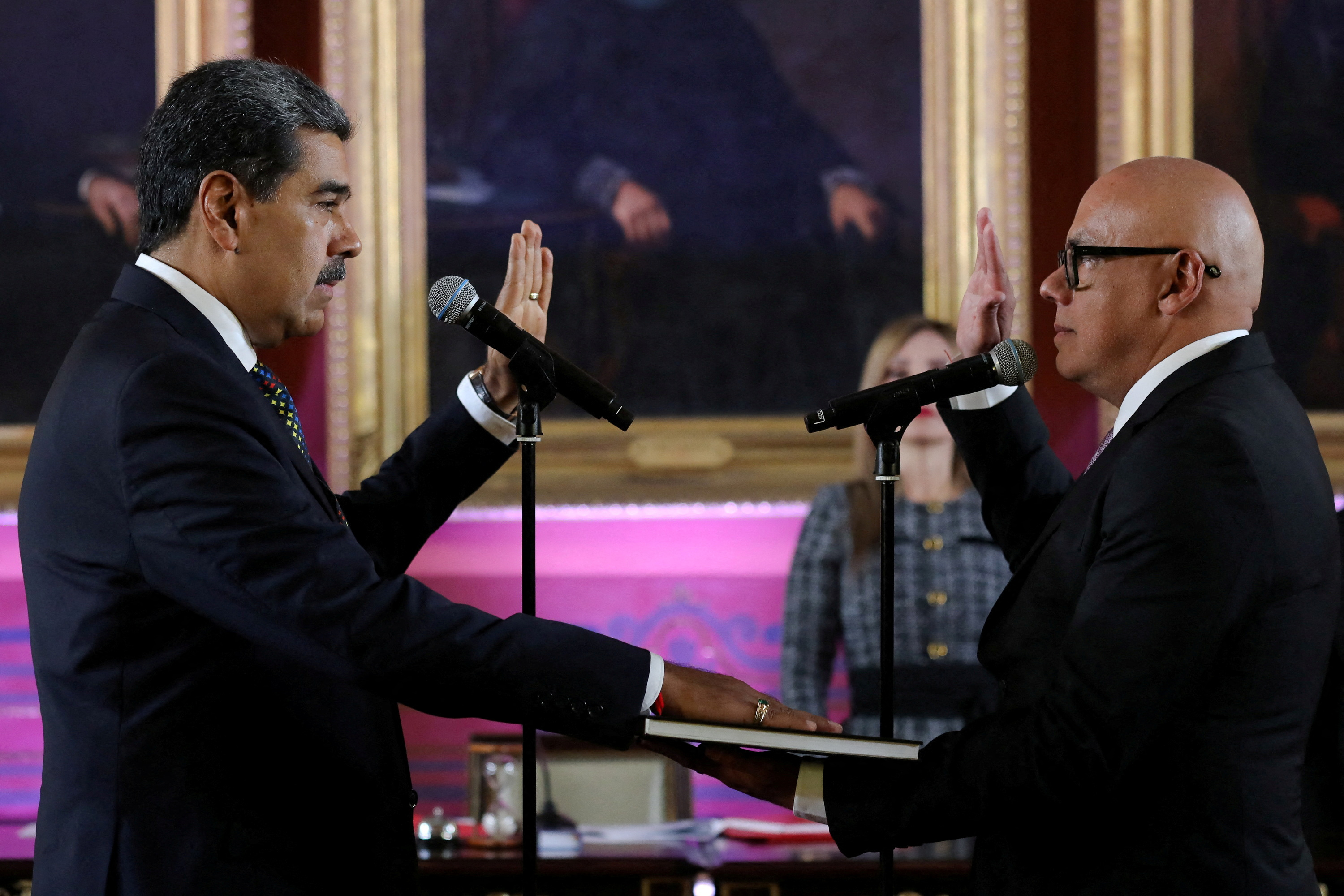 Nicolas Maduro places his hand on a book and lifts the other hand to swear the oath of office.