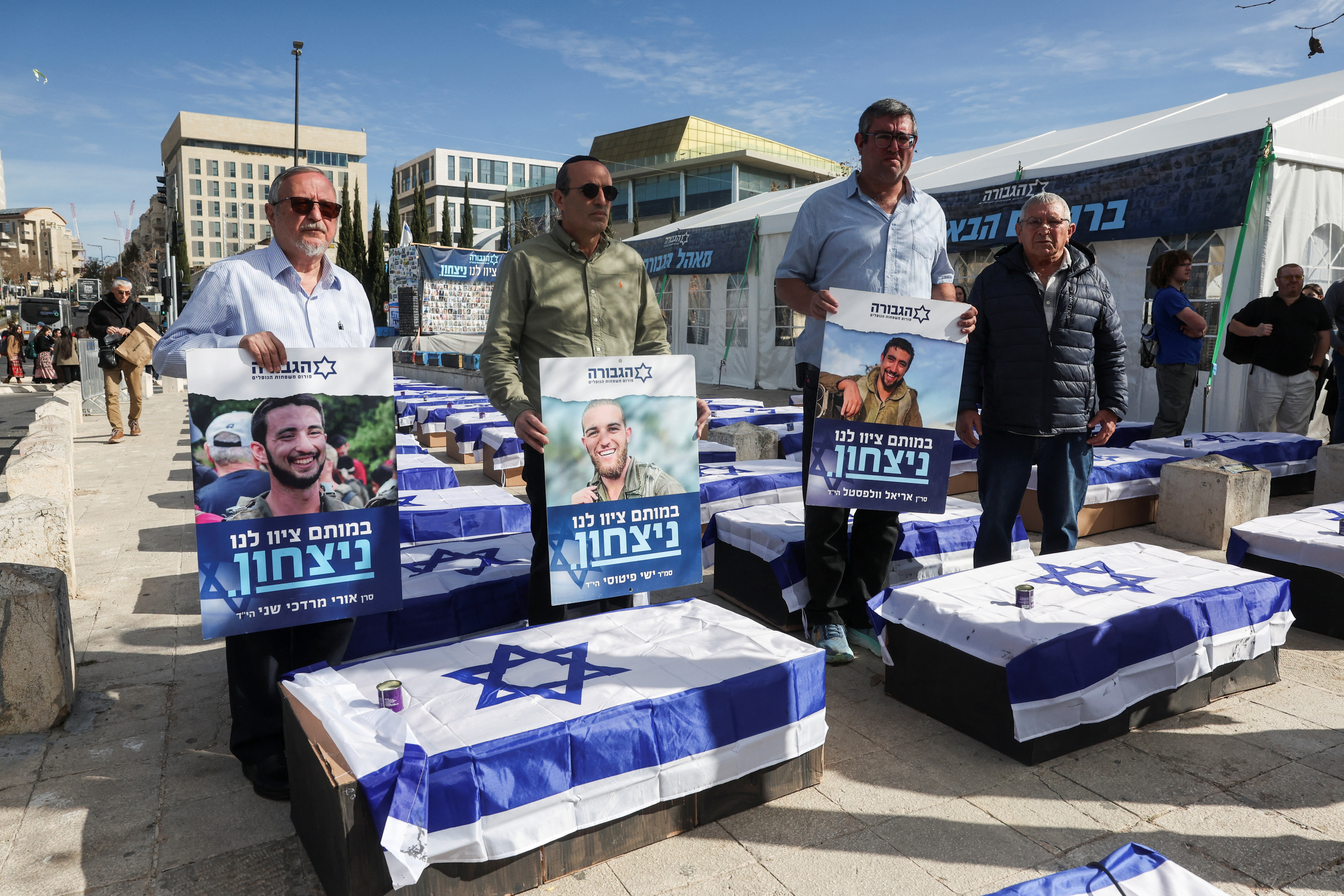 People stand next to an installation of coffins draped with Israeli flags representing the blood that, according to a protest group representing fallen Israeli soldiers, will be shed as a result of a ceasefire deal, in Jerusalem, January 16, 2025. REUTERS/Ronen Zvulun