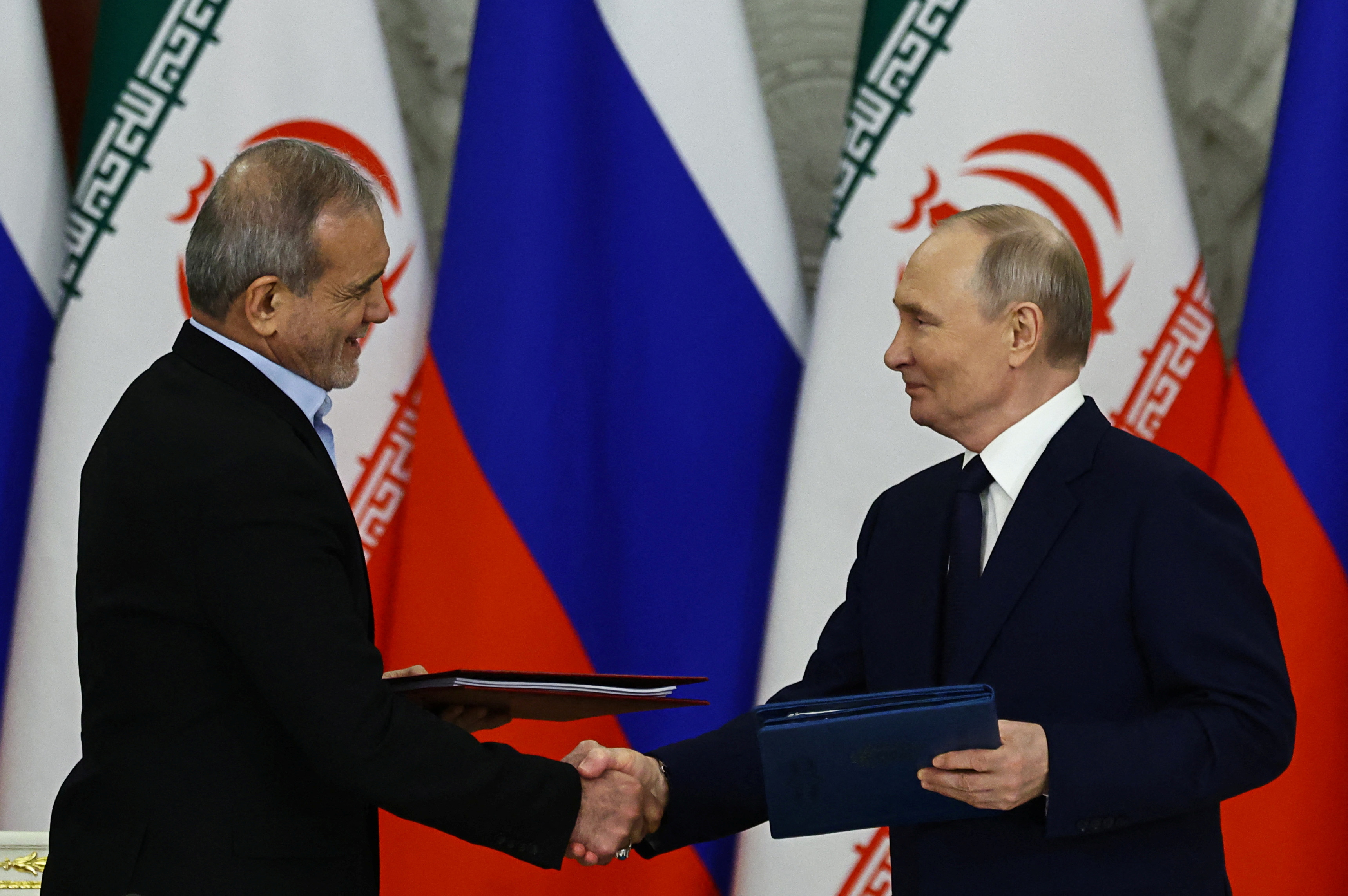 Russian President Vladimir Putin and Iranian President Masoud Pezeshkian shake hands