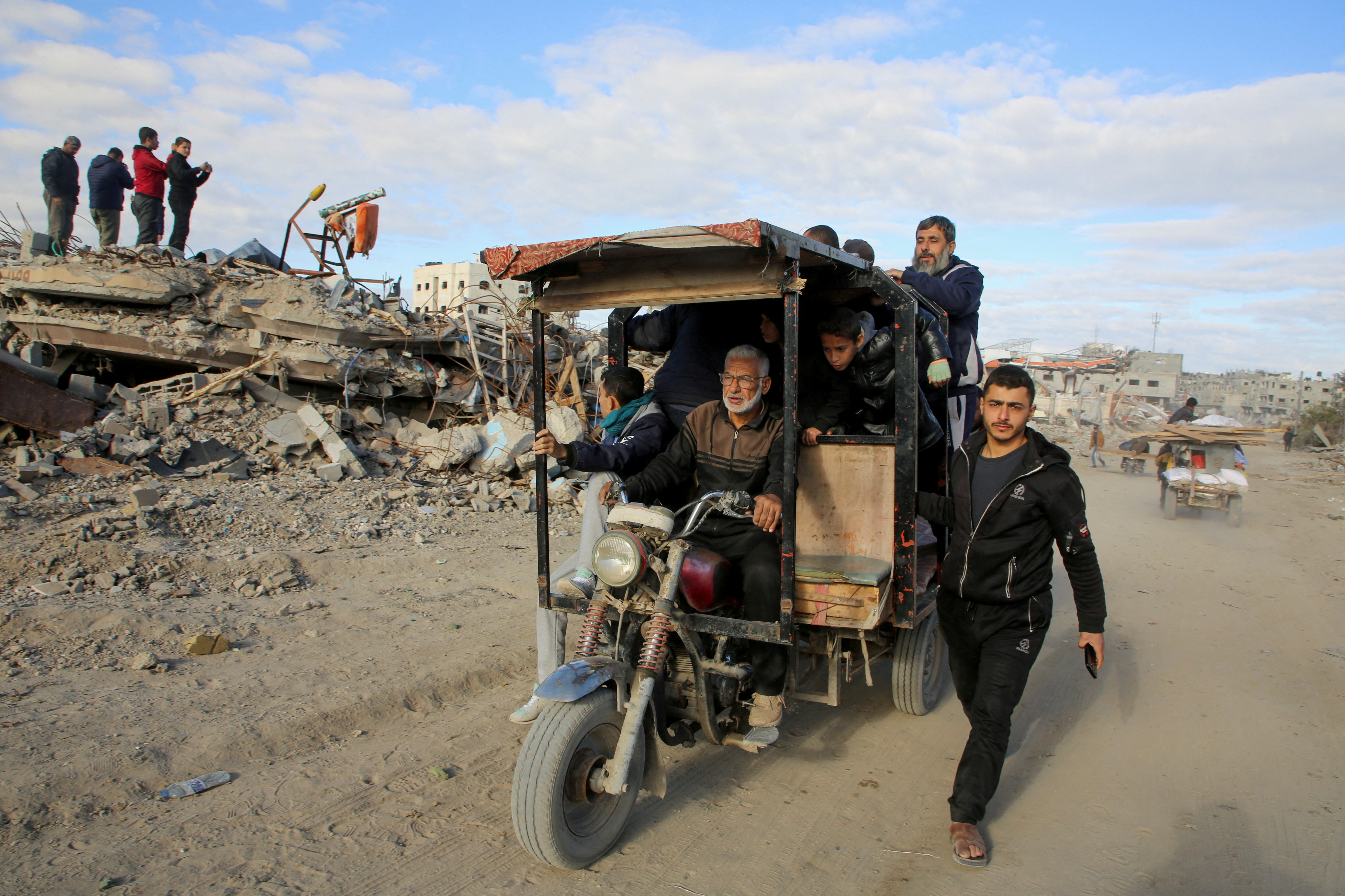 Palestinians ride a vehicle past the rubble of houses and buildings destroyed during the war, following a ceasefire between Israel and Hamas, in Rafah in the southern Gaza Strip