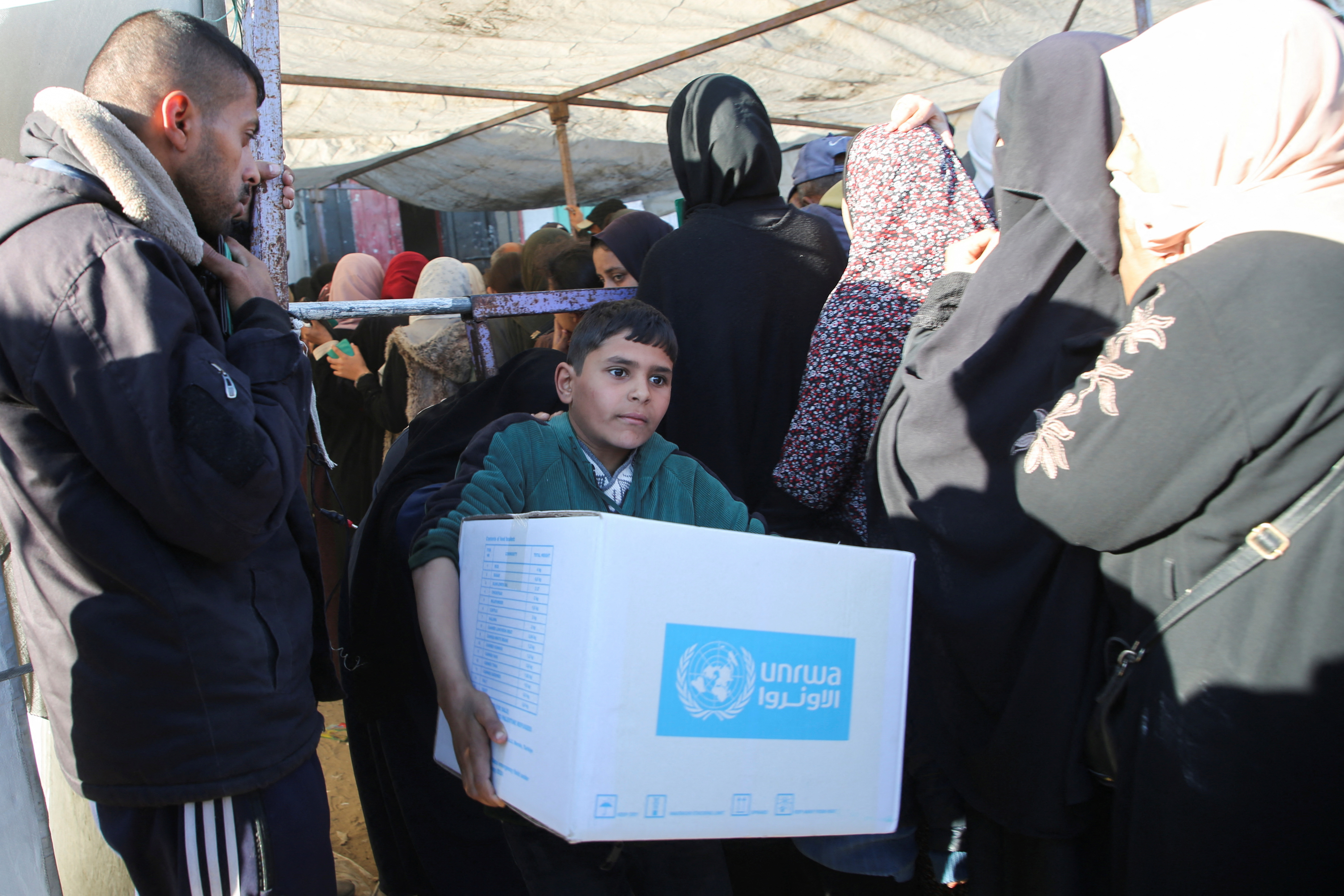 A Palestinian boy carries an aid box provided by UNRWA in Khan Younis in January 2025