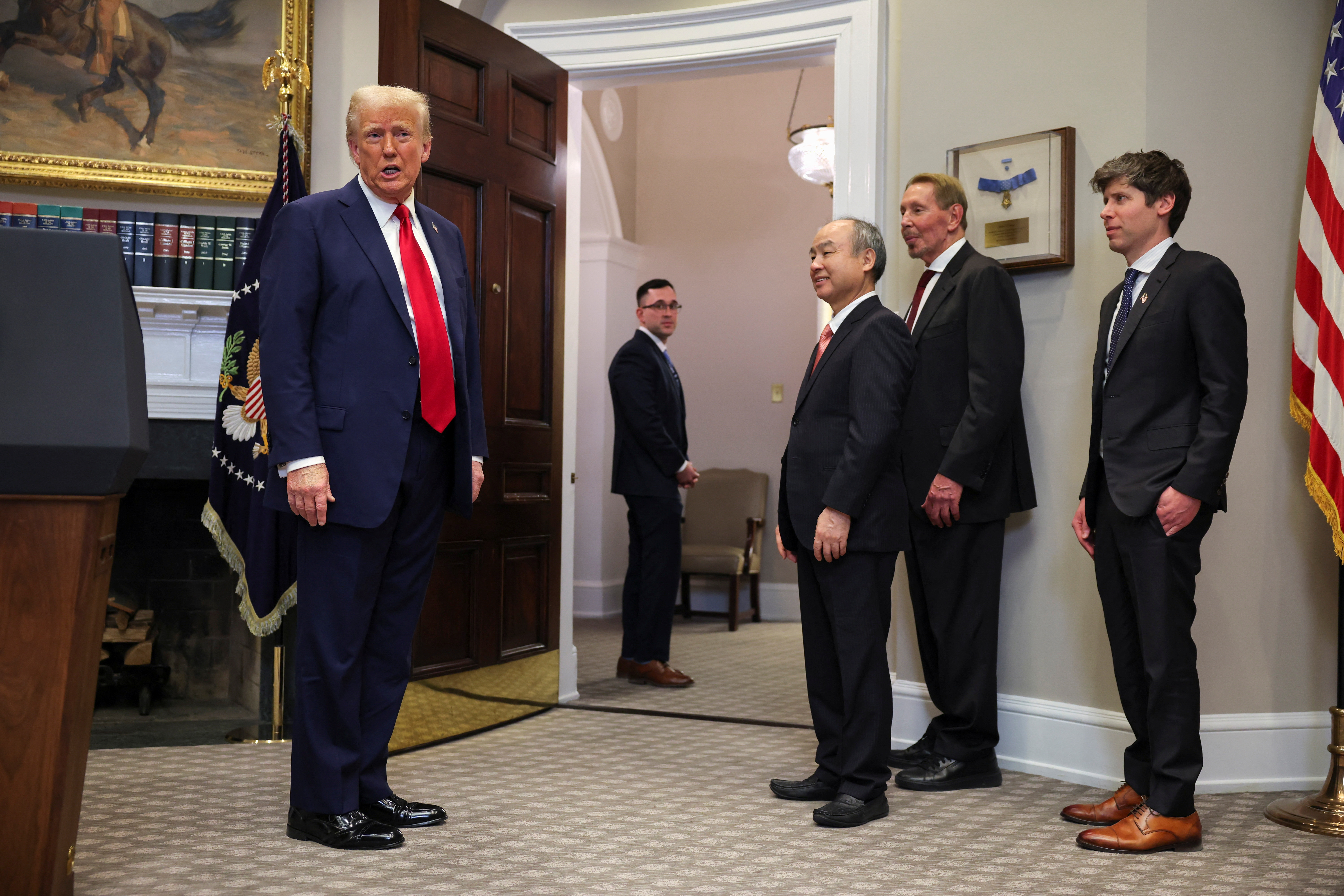 Donald Trump stands nex to Oracle head Larry Ellison and other tech leaders at the White House.