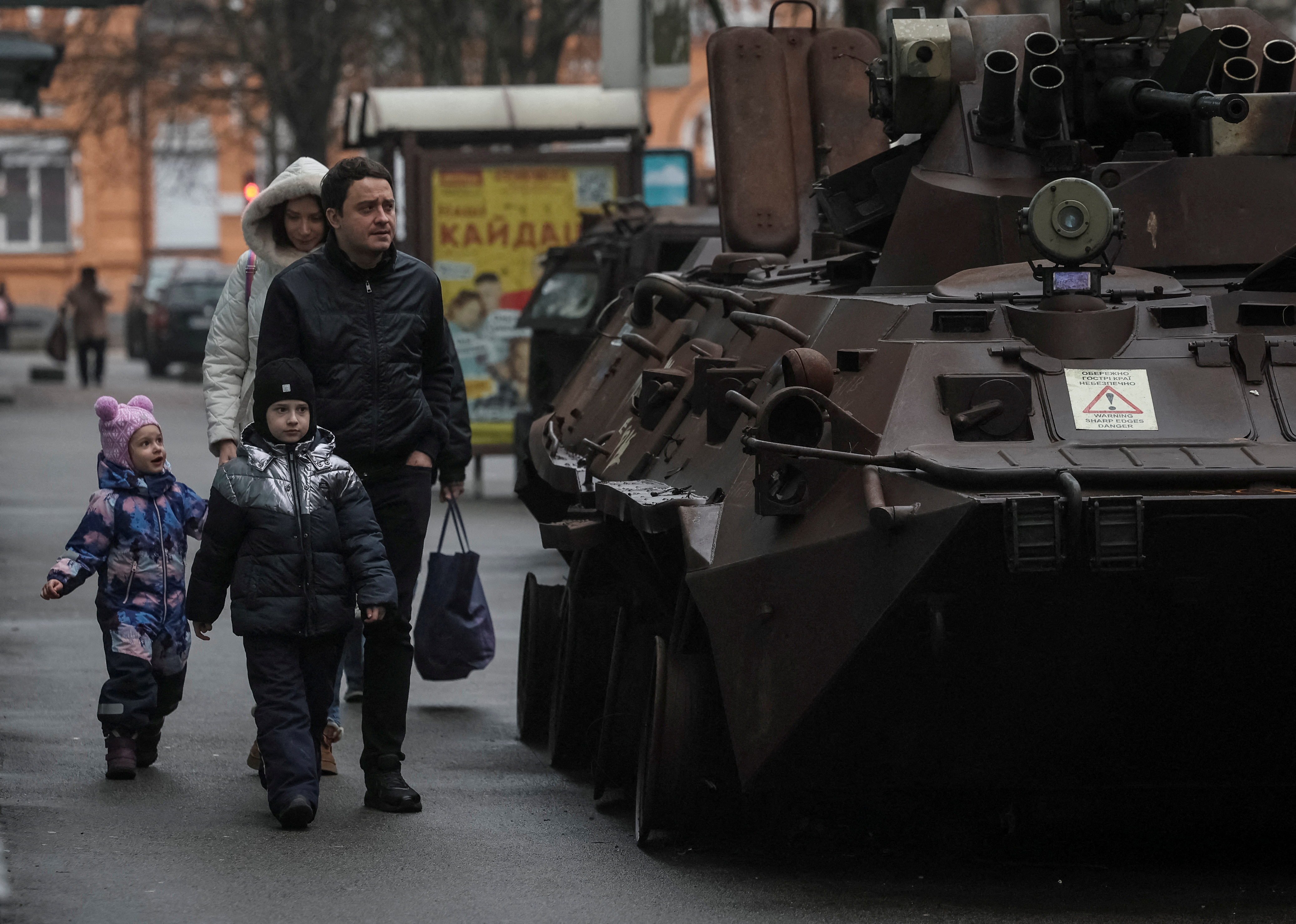 People walk past a street exhibition displaying destroyed Russian military vehicles.