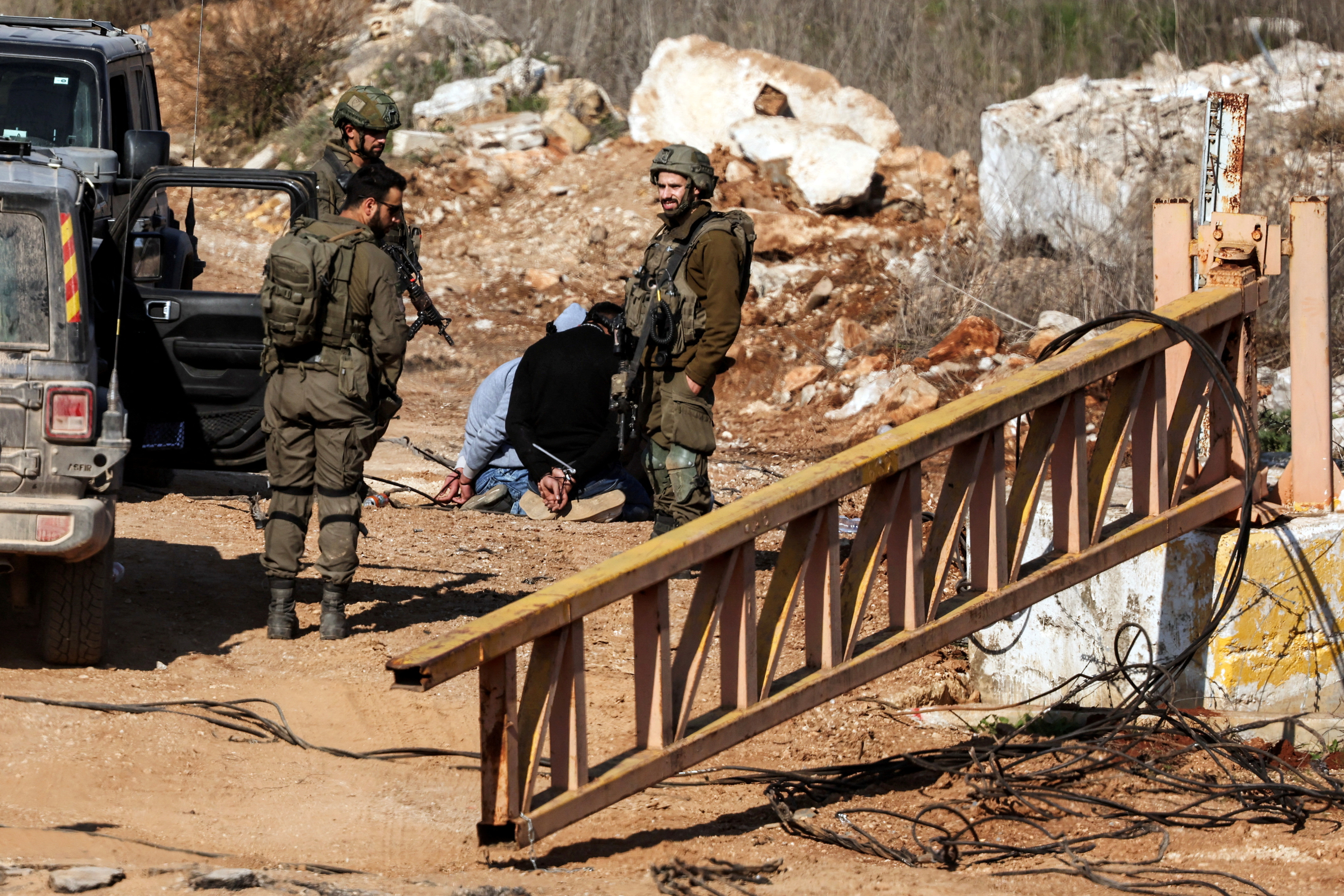Israeli soldiers stand near Lebanese detainees at the Israeli-Lebanese border.
