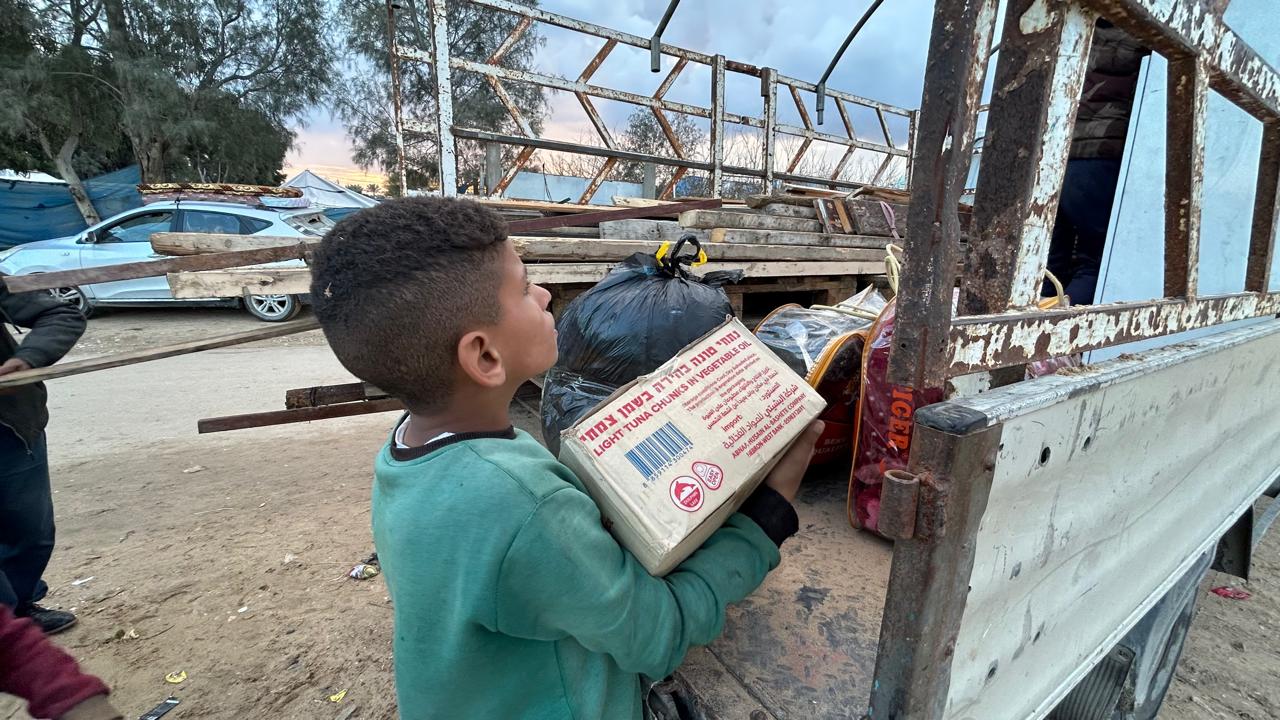Boy lifts a box onto the back of a pick-up truck
