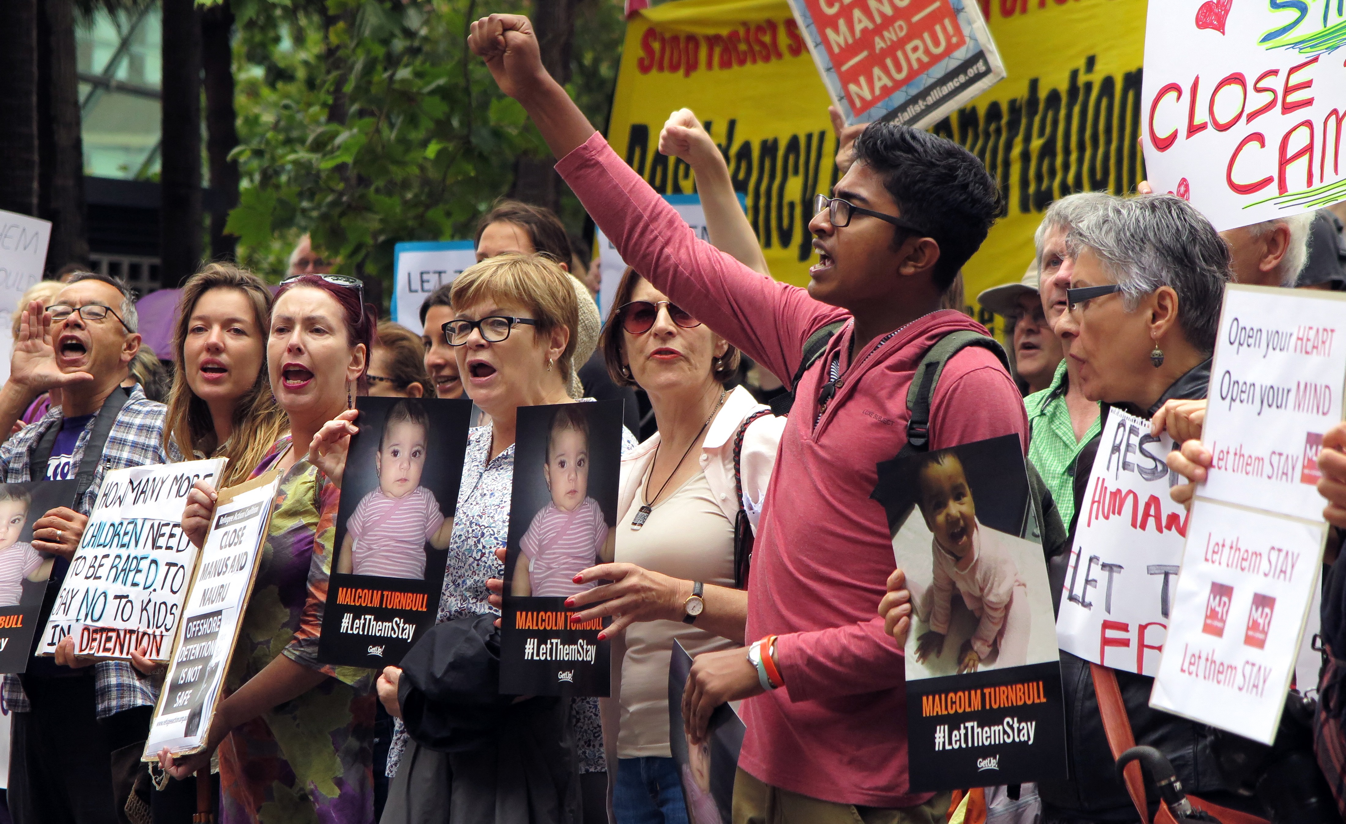 People hold up placards at a protest outside an immigration office in Sydney on February 4, 2016, as Australian church leaders said they would offer sanctuary to asylum-seeker adults and children set to be deported to a remote Pacific camp after a court ruling, saying they were willing to defy the government's harsh immigration policy. Under Canberra's hardline immigration policy, asylum-seekers including children who try to reach Australia by boat are sent to offshore detention centres in Papua New Guinea and Nauru, where they are held indefinitely while refugee applications are processed. They are blocked from being resettled in Australia even if found to be genuine refugees. AFP PHOTO / WILLIAM WEST (Photo by WILLIAM WEST / AFP)