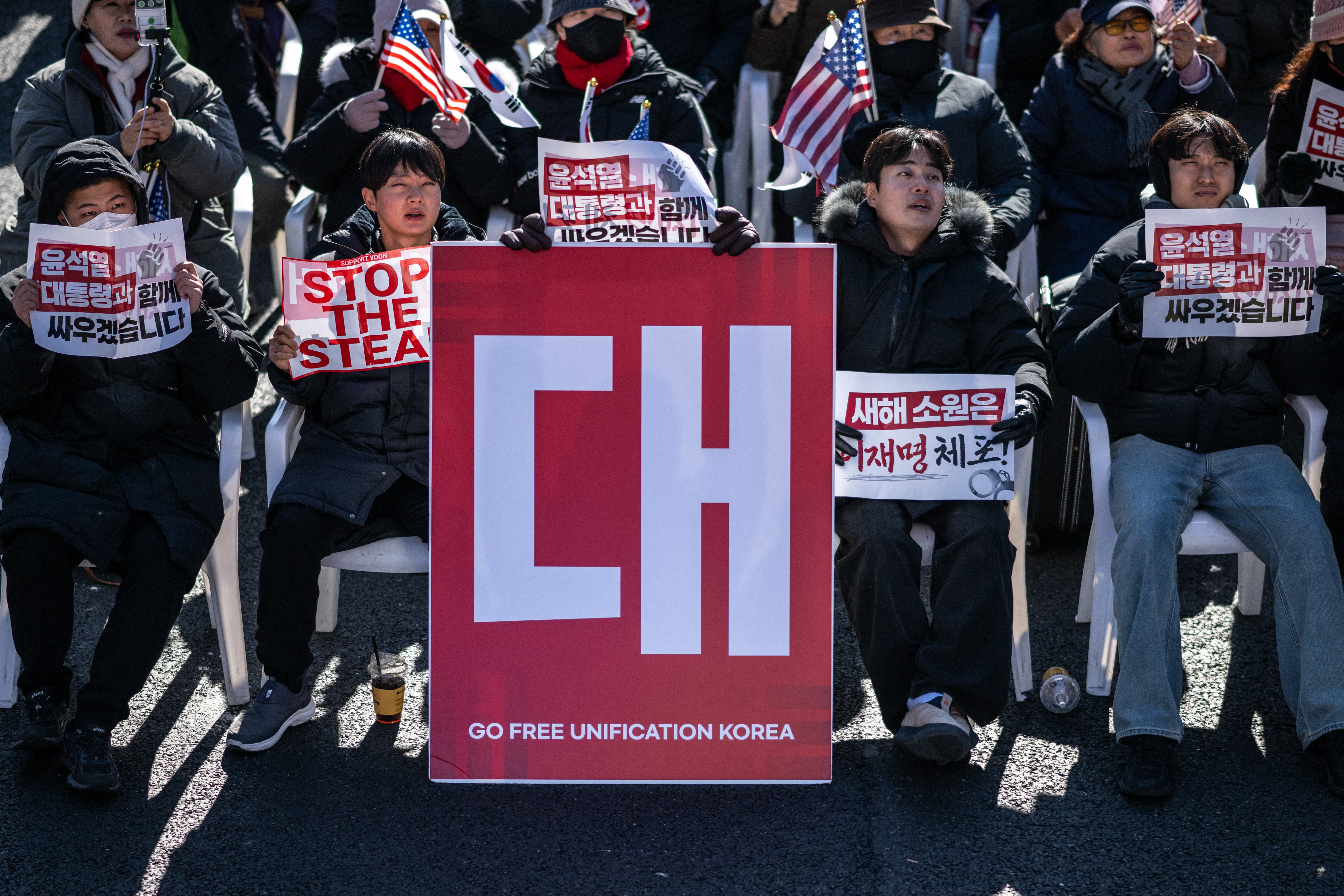 TOPSHOT - Demonstrators sit beside a board that reads "Go Free Unification Korea" (C) during a rally in support of impeached South Korea president Yoon Suk Yeol in the Gwanghwamun area of Seoul on January 4, 2025. South Korea's political leadership was in uncharted territory January 4 after the sitting president resisted arrest over a failed martial law decree days before the warrant expires. (Photo by Philip FONG / AFP)