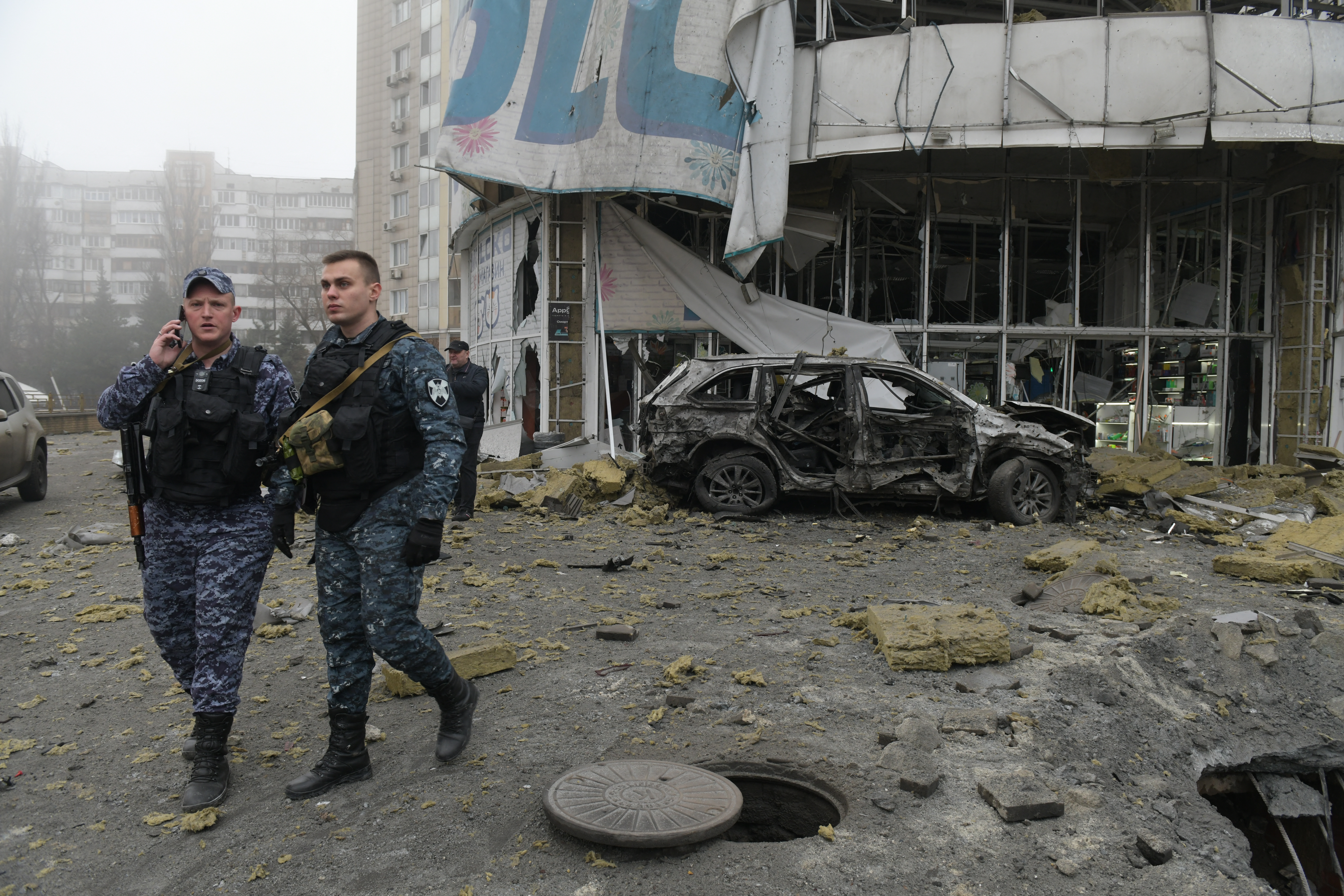 Law enforcement officers near a damaged store following shelling in Donetsk