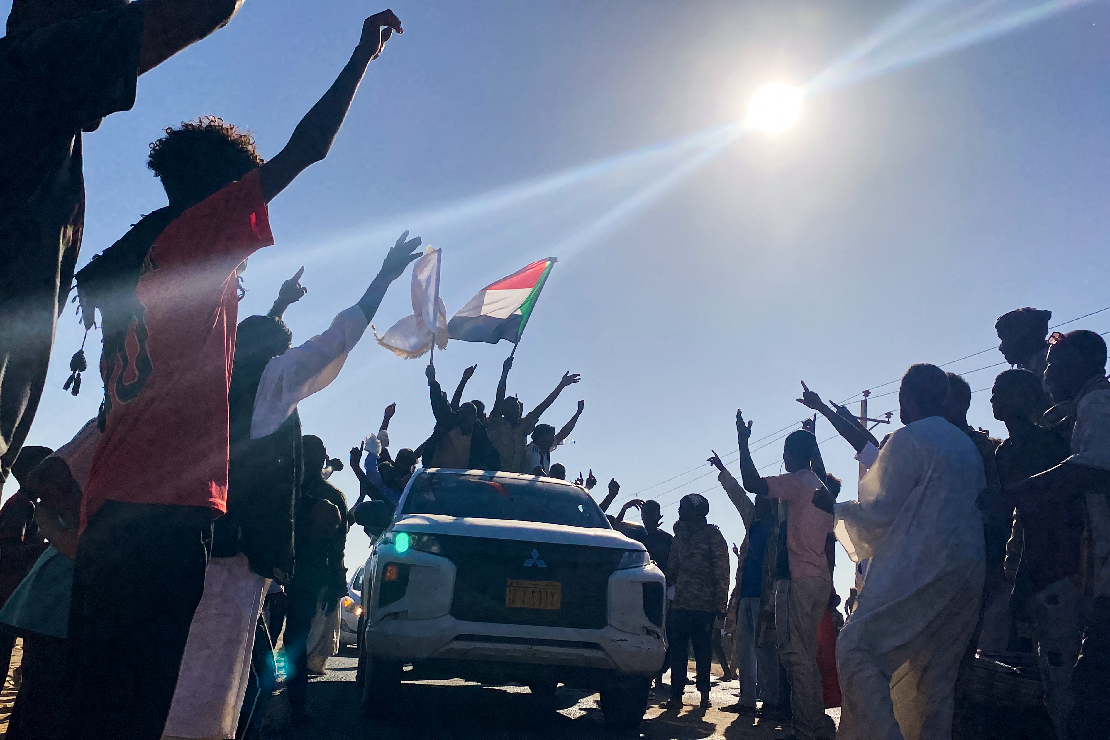 Sudanese people celebrate with passengers of passing vehicles.