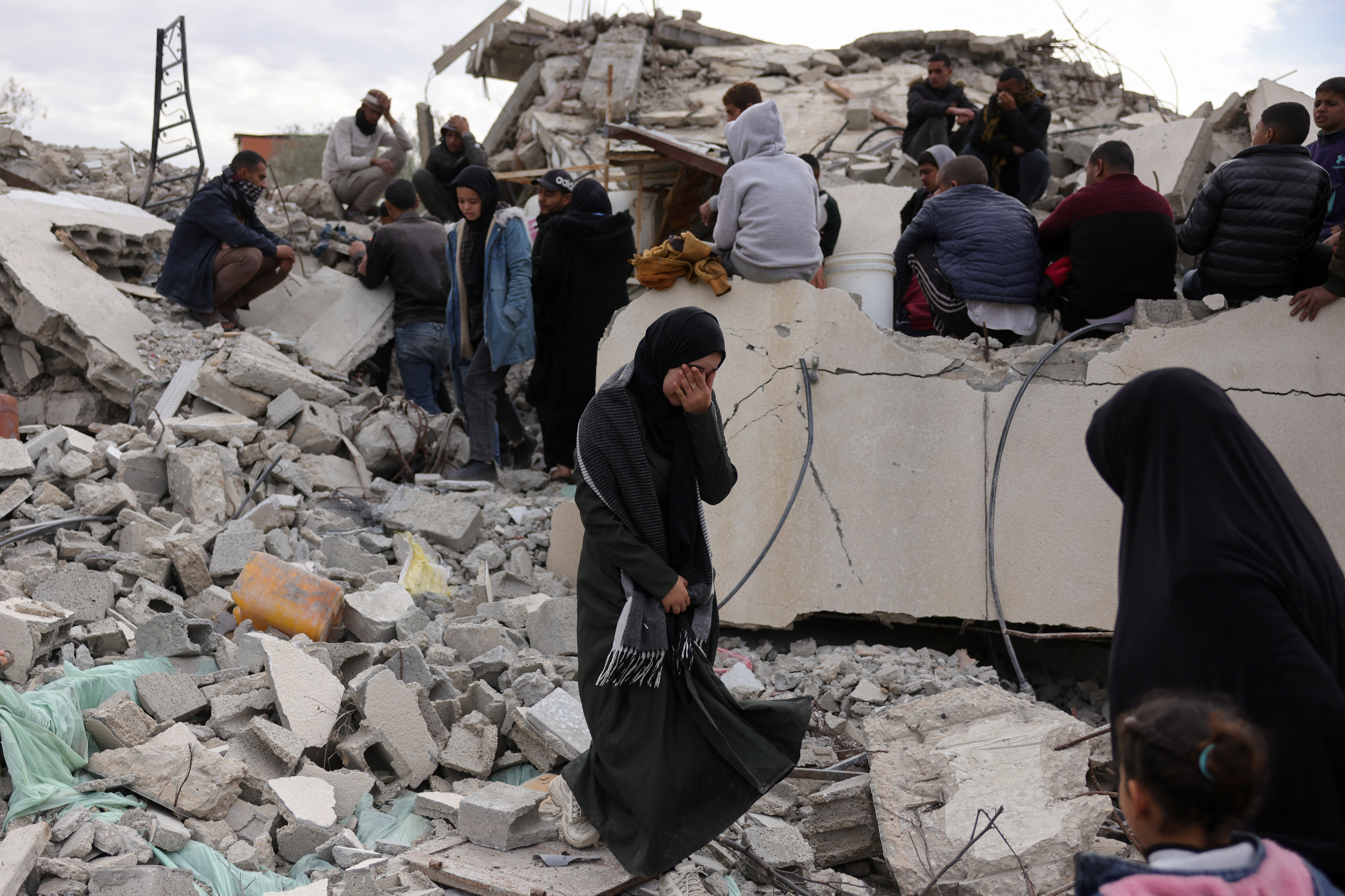people sit on a destroyed building crying
