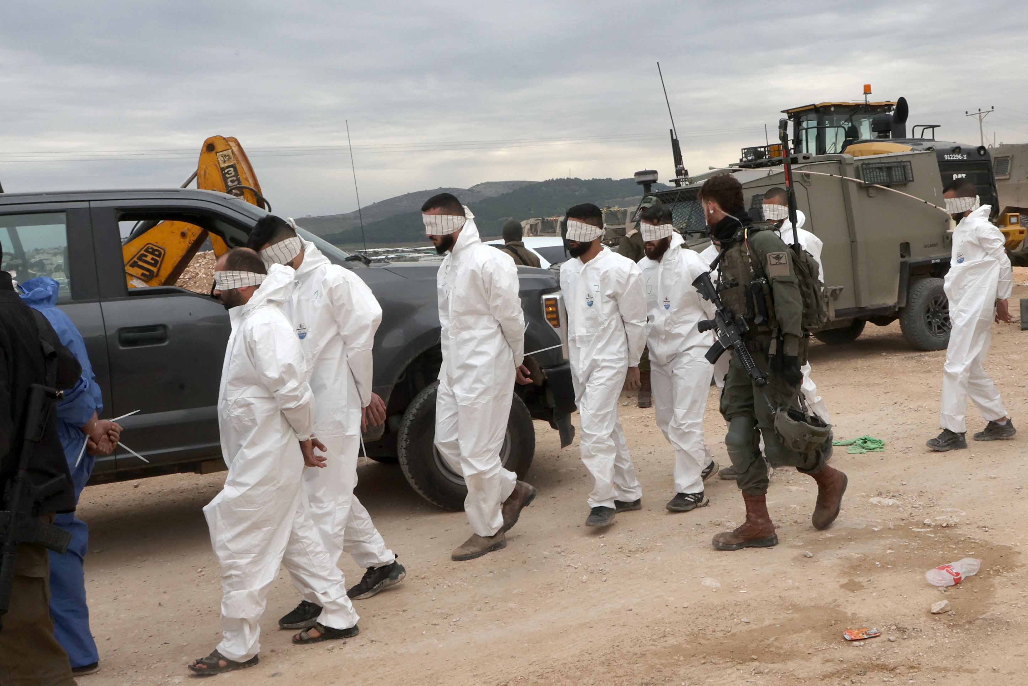 Israeli soldiers transfer Palestinian men arrested during a military raid on Jenin, near the Muqeibila crossing on the border with the occupied-West Bank, on January 22, 2025. Gunfire and explosions rocked the Jenin area of the occupied West Bank on January 22, an AFP journalist reported, as the Israeli military kept up a large-scale raid for a second day. (Photo by GIL COHEN-MAGEN / AFP)