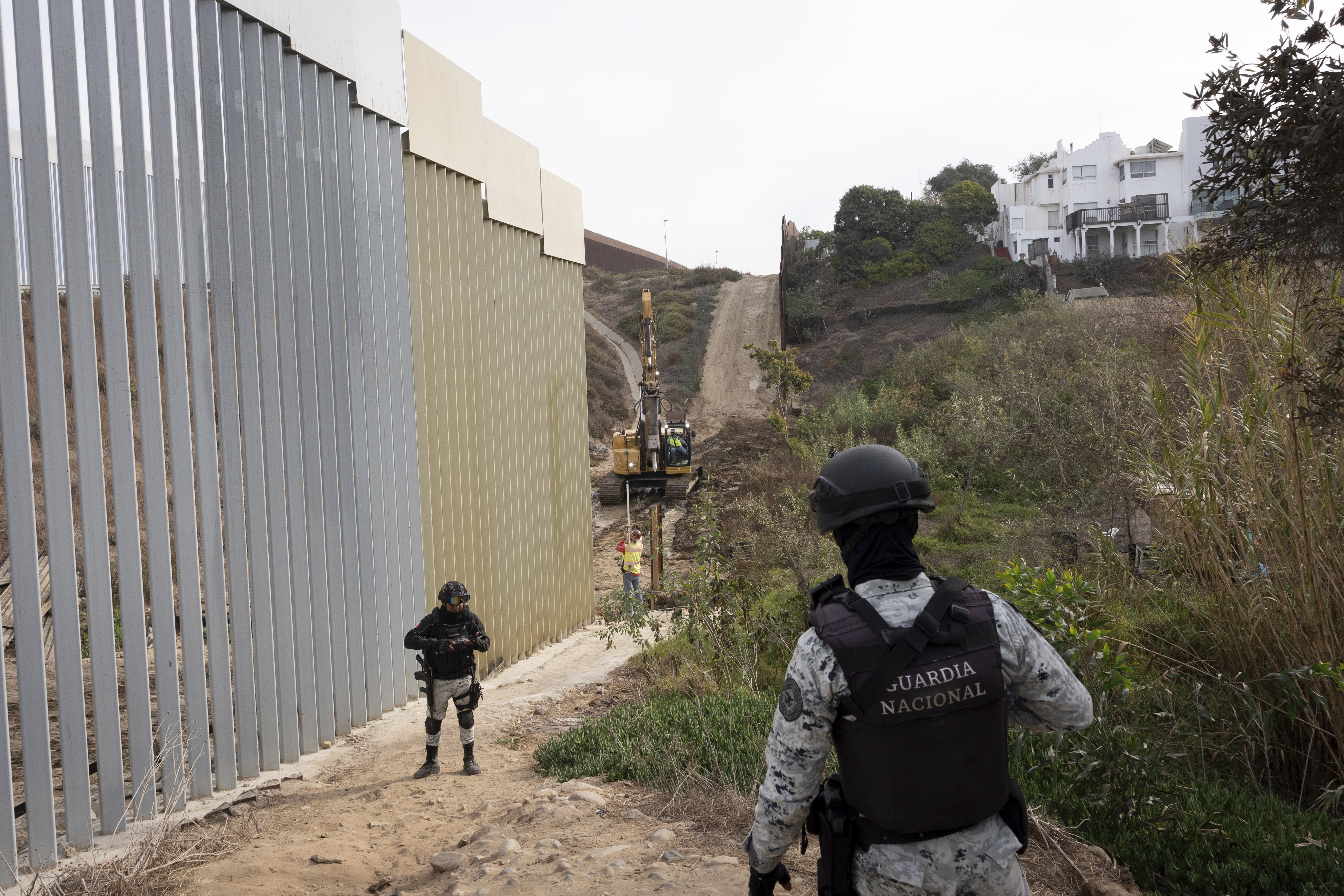 Members of the Mexican National Guard patrol the US-Mexico border wall.