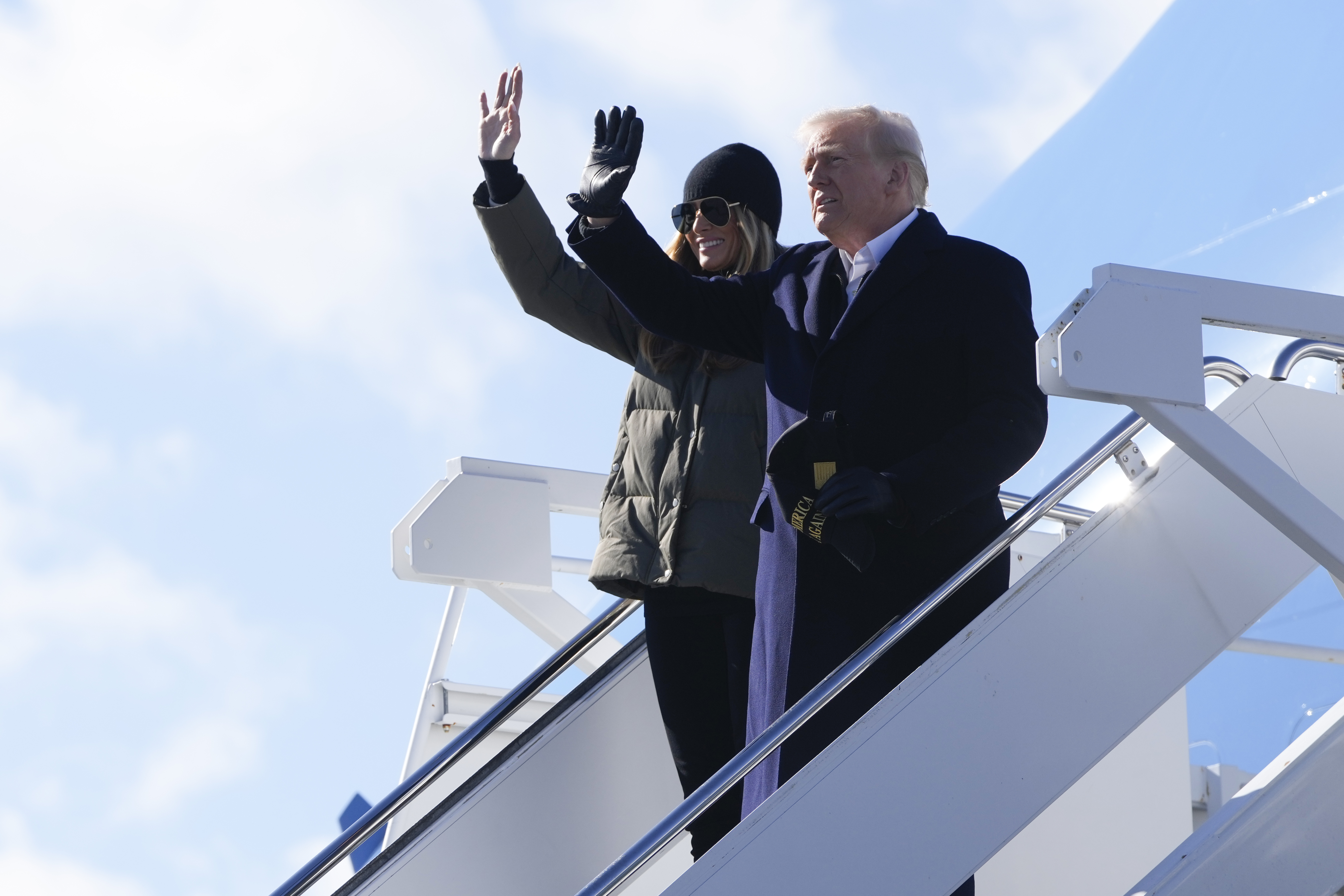 Donald and Melania Trump wave as they walk down steps of Air Force One.