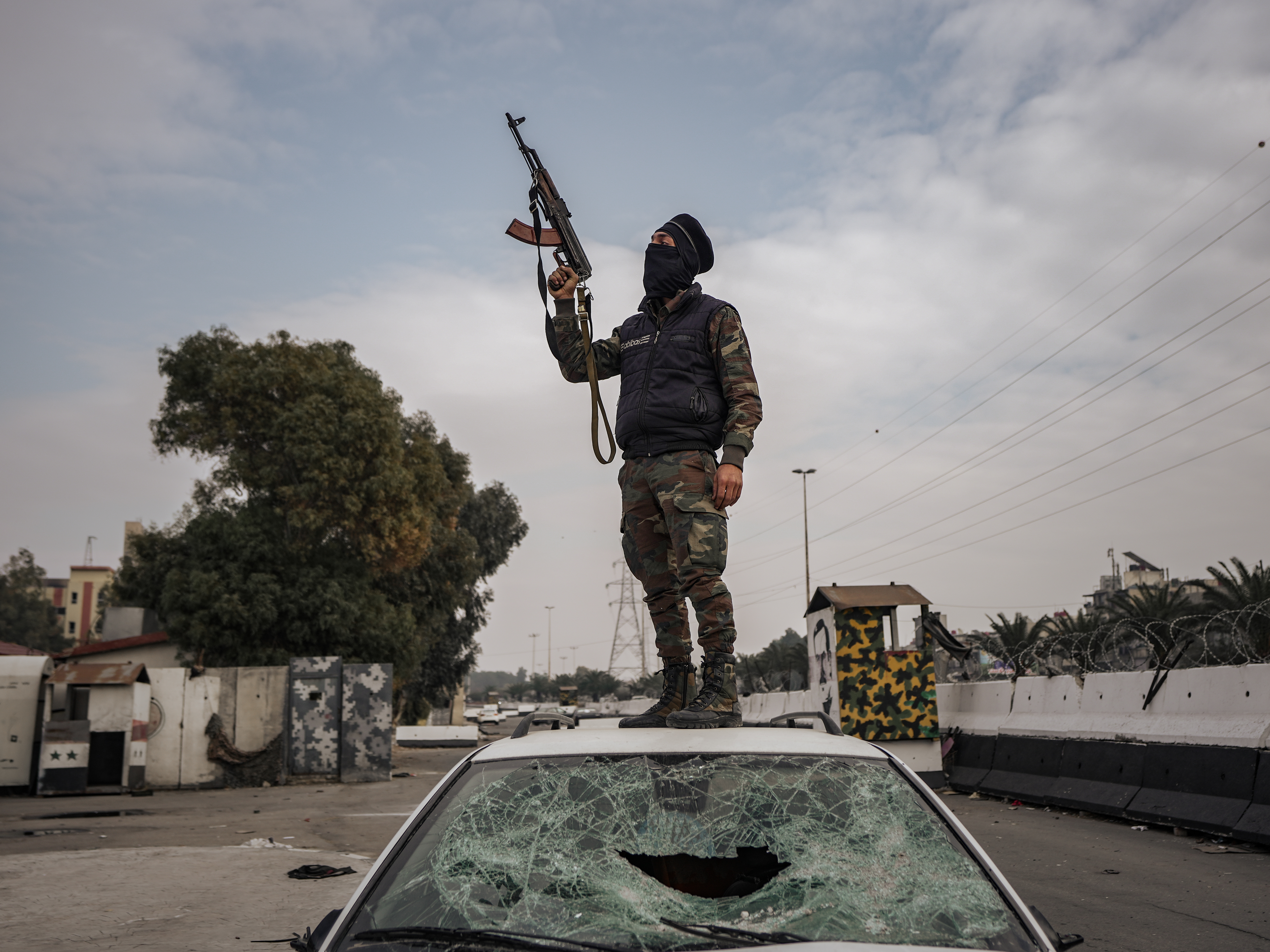 A fighter from the Syrian Operations Administration stands on a car belonging to Bashar al- Assad's regime, celebrating the liberation of the "Palestine Branch" prison, December 20, 2024