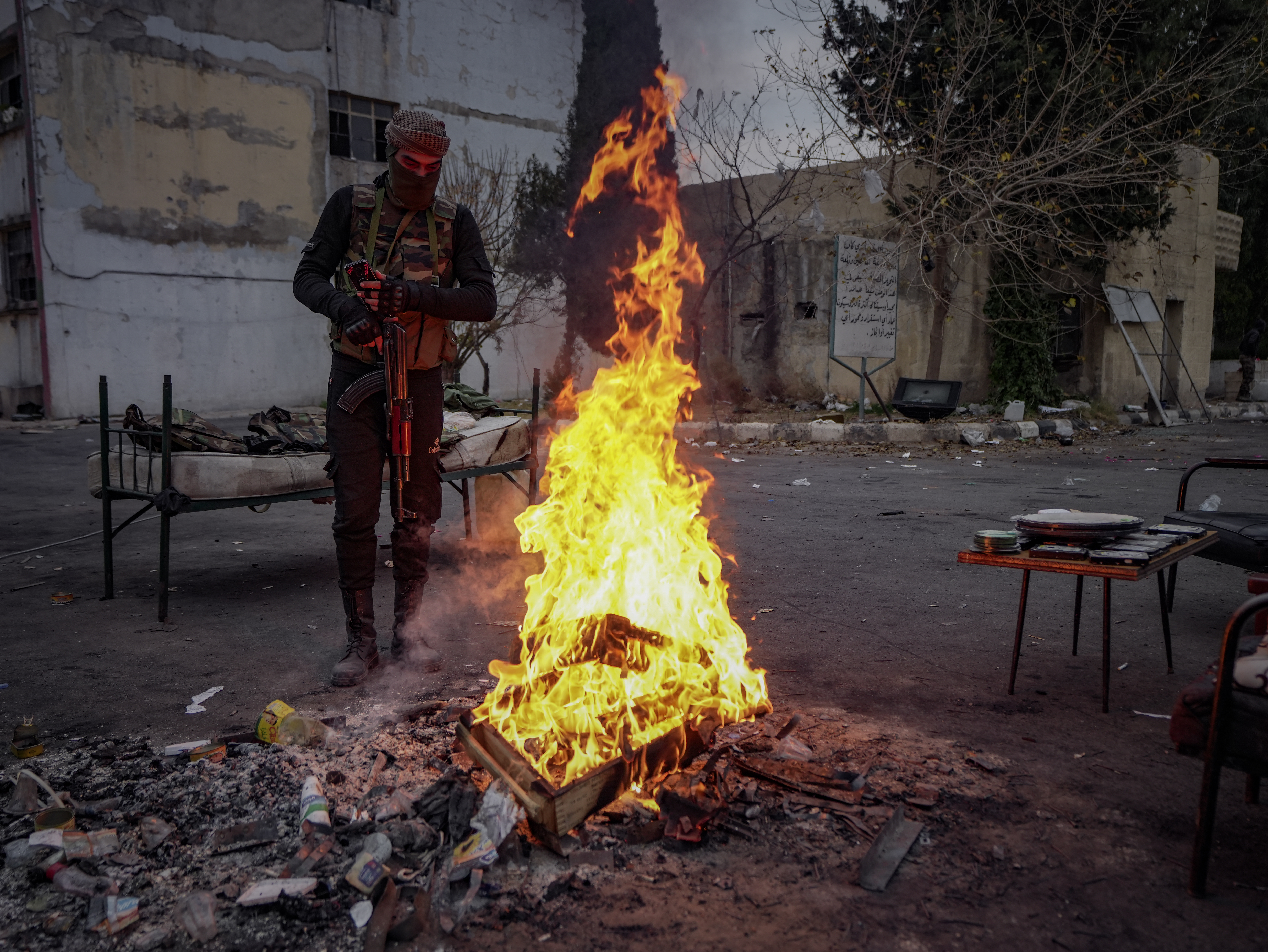 A fighter from the Syrian Military Operations Administration burns some remnants of the former Syrian army in the yard of the "Palestine Branch" prison: December 20, 2024.