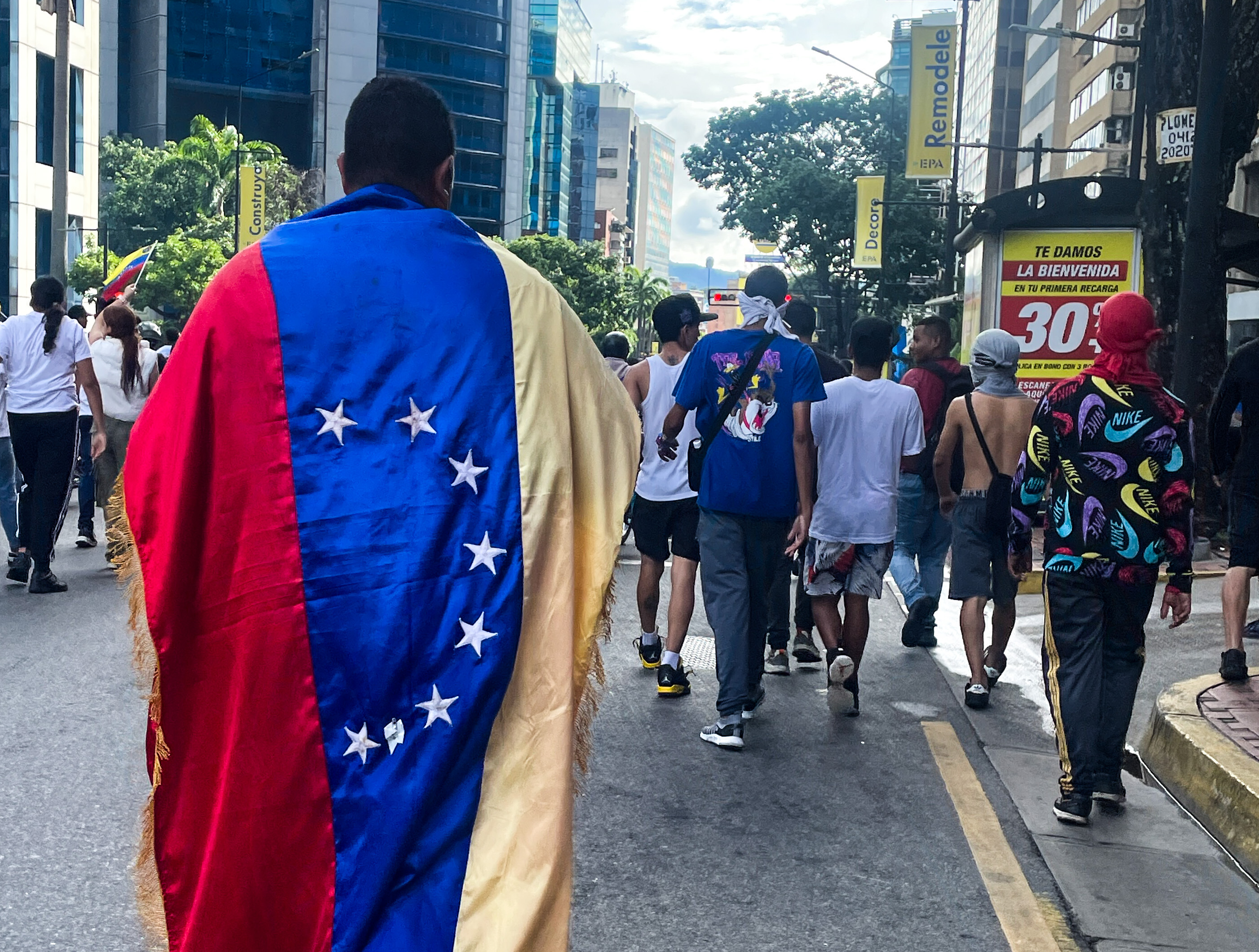 A man draped in the Venezuelan flag walks through post-election protests in Caracas.