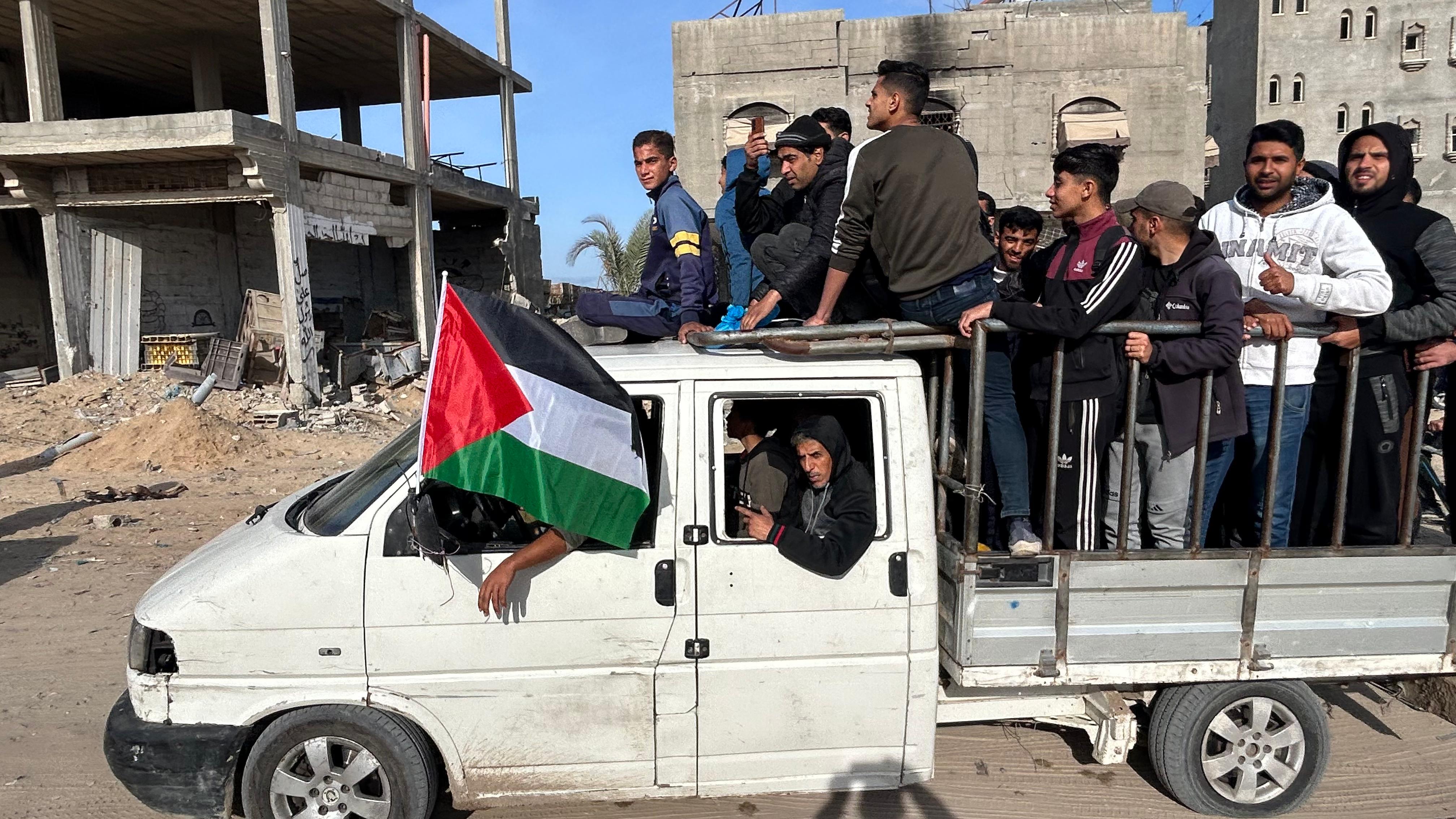 A pick up truck carrying a group of men and a Palestinian flag